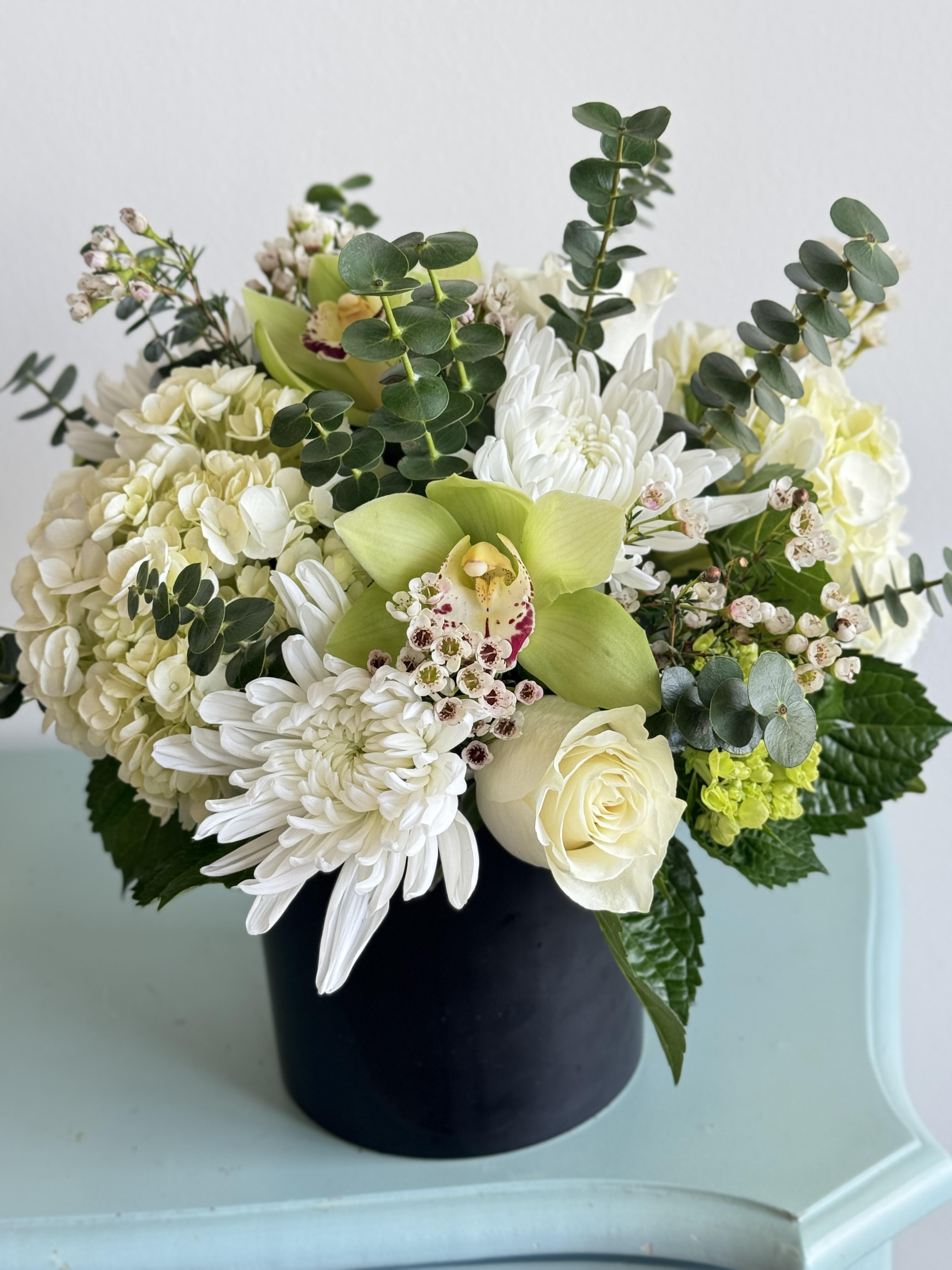 White and green floral arrangement in a black vase