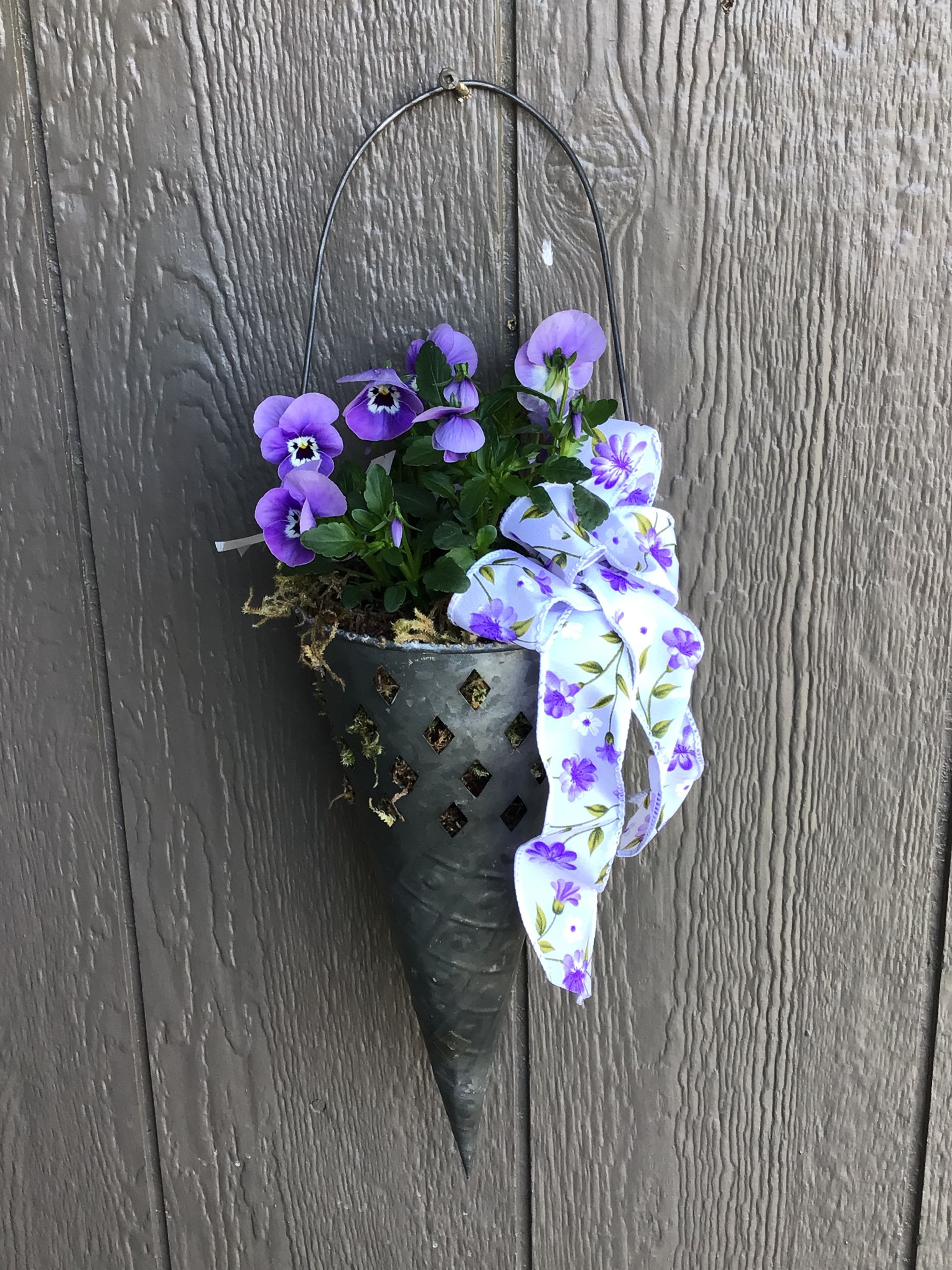 Garden Plant Hanger  - A garden plant hanger filled with a seasonal plant that can be hung on a door, fence or anywhere else in the yard to enjoy that seasonal pop of color