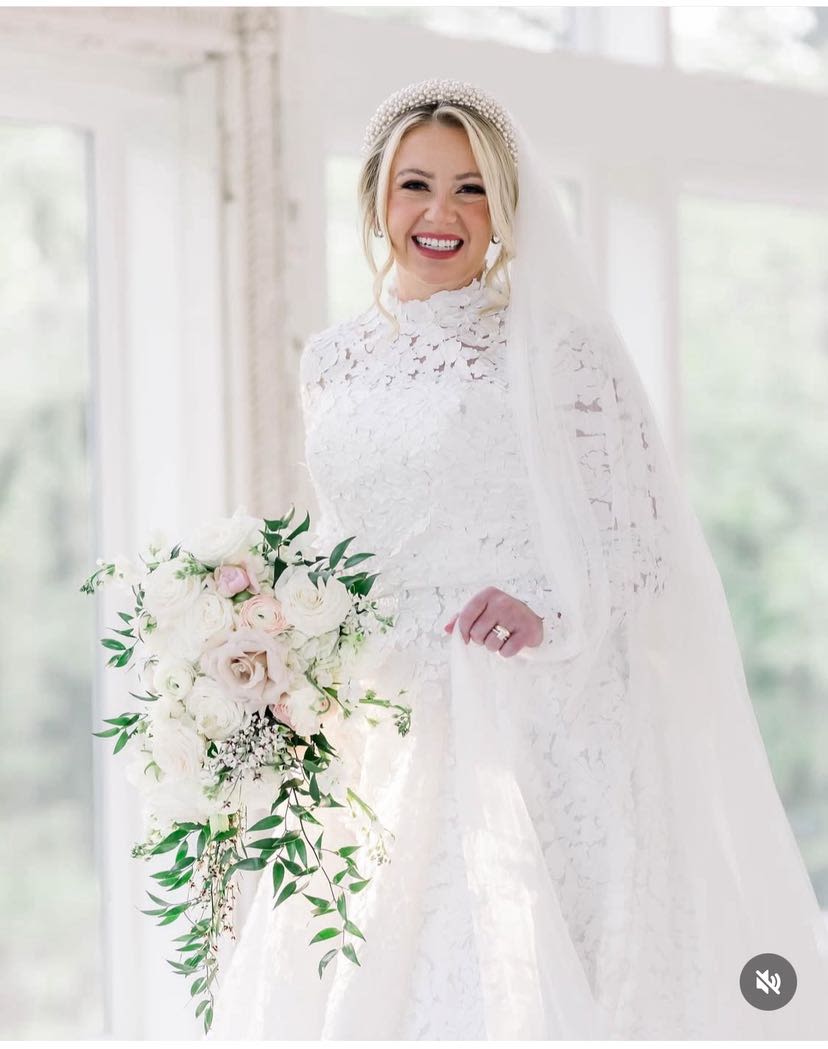 Bride in a white lace gown holding a cascading bouquet of white and blush flowers
