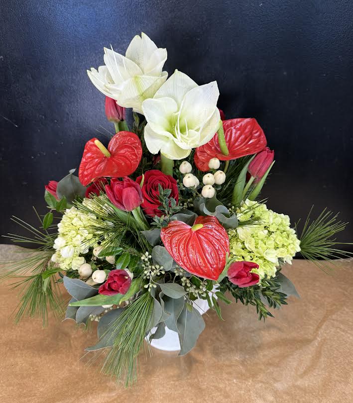 Red and white floral arrangement with tulips, anthuriums, and lilies in a white vase