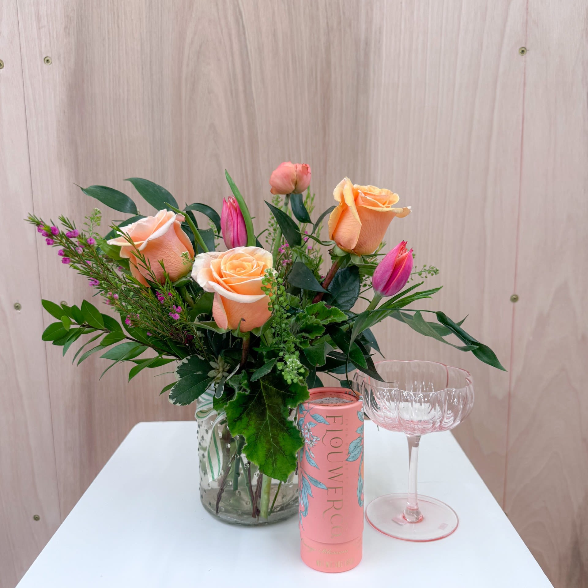 Cheers! Gift Set - Toast to that special person in your life! This gift set includes a beautiful petite arrangement in shades of peach and pink, a pink flower shaped coupe glass, and orange blossom finishing sugar. Upgrade to deluxe or premium for additional luxe blooms in the arrangement.