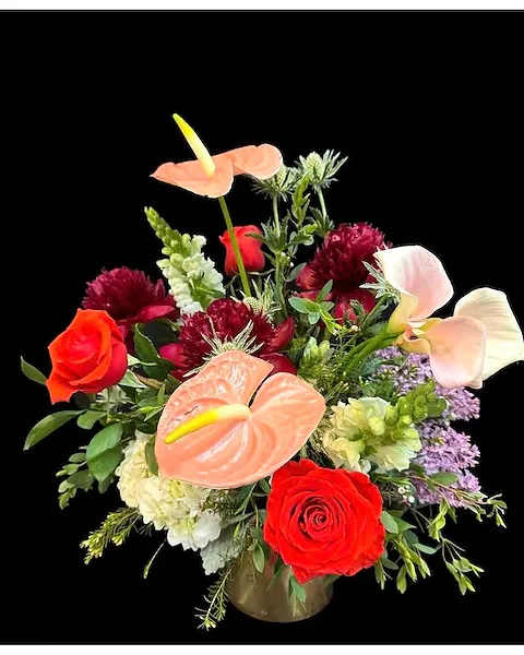 Mixed bouquet with red roses and peach calla lilies in a vase
