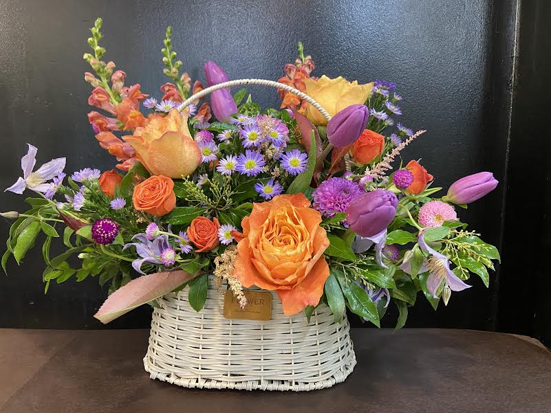 Basket arrangement with orange and purple flowers
