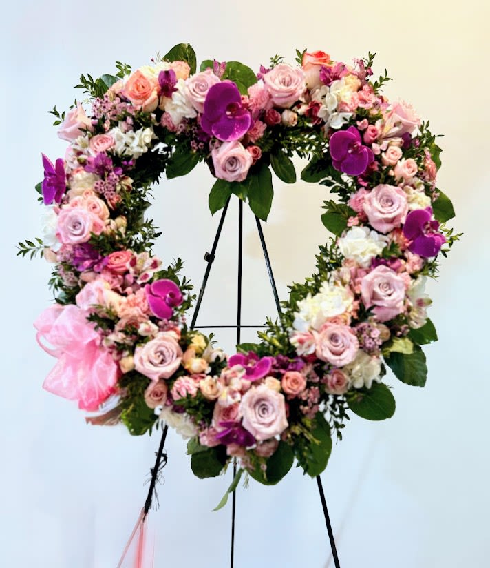 Large floral wreath of pink and purple blooms on a black stand