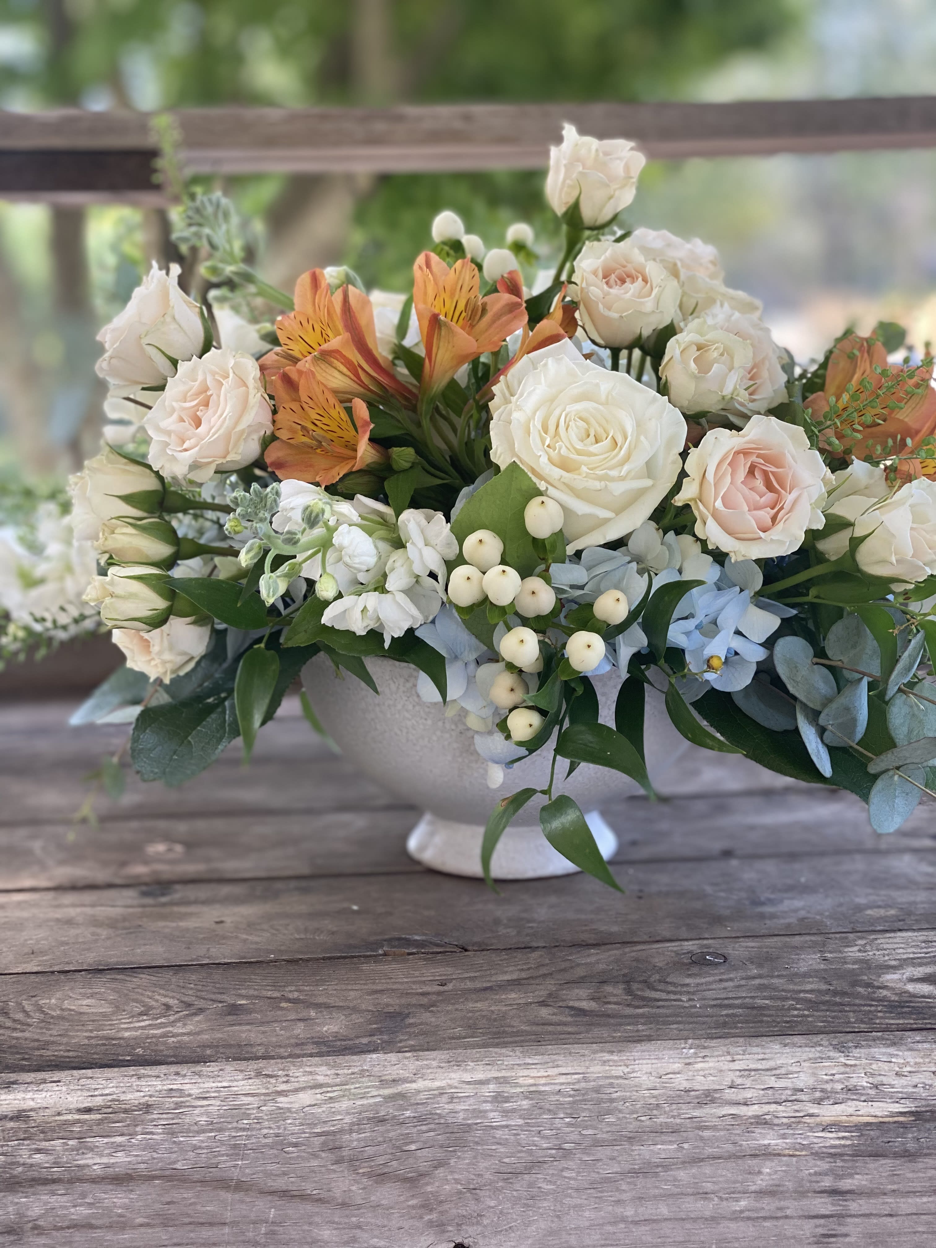 Exquisite Taste   - Elevate Your Space with Timeless Elegance Introducing "Exquisite Taste," a sophisticated arrangement set in a classic ceramic white compote, brimming with a variety of soft-colored blooms. This elegant display is perfect for enhancing any entry table, centerpiece, or bedside table, adding a touch of refined beauty to your home. **Soft Color Blooms: A harmonious blend of pastel hues creates a serene and inviting atmosphere, ideal for any setting. **Ceramic White Compote: The timeless design of the compote complements the delicate flowers, offering a chic and versatile decorative piece. **Versatile: Whether used as a welcoming entryway piece, a stunning centerpiece, or a gentle bedside accent, this arrangement adds elegance and charm to any room. Choose "Exquisite Taste" from Elizabeth's Garden to bring a touch of sophistication and grace to your space, perfect for those who appreciate refined beauty and exquisite design. 