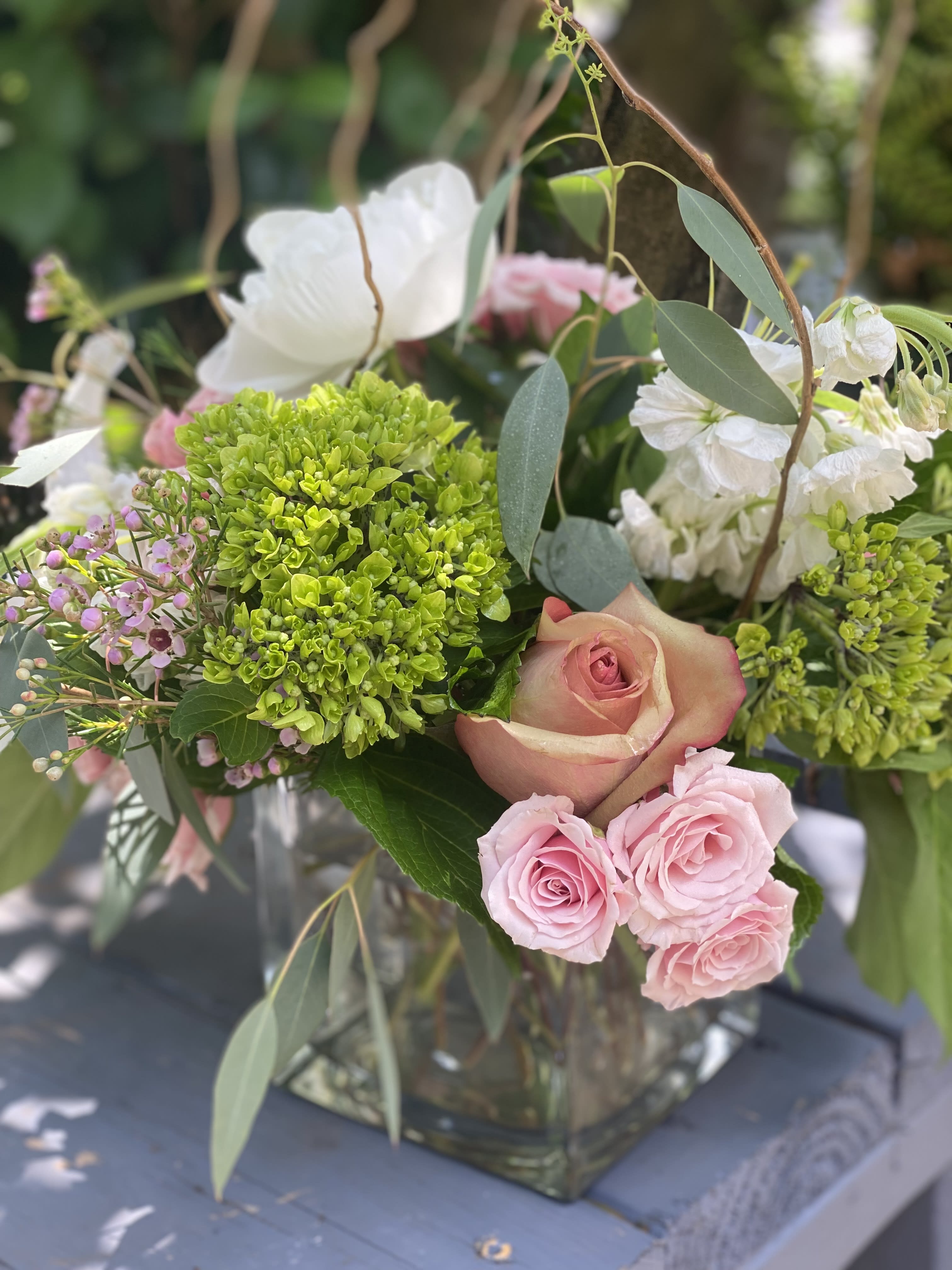 Twiggy - Charming Novelty with a Natural Touch Meet "Twiggy," a cute and charming novelty arrangement designed to captivate with its unique blend of natural elements. This delightful bouquet is crafted in a clear glass cube, featuring a selection of favorite blooms like roses, lilies, and stock, beautifully accented with natural twigs. Unique Design: The clear glass cube provides a modern and elegant base, allowing the vibrant colors and textures of the flowers and twigs to shine. Favorite Blooms: Includes a harmonious mix of roses, lilies, and stock, offering a variety of seasonal colors and fragrances. Natural Accents: The addition of natural twigs adds an organic and rustic charm, making this arrangement truly one-of-a-kind. Choose "Twiggy" from Elizabeth's Garden to bring a touch of nature's whimsy into your space, perfect for those who appreciate a blend of elegance and novelty in their floral arrangements.