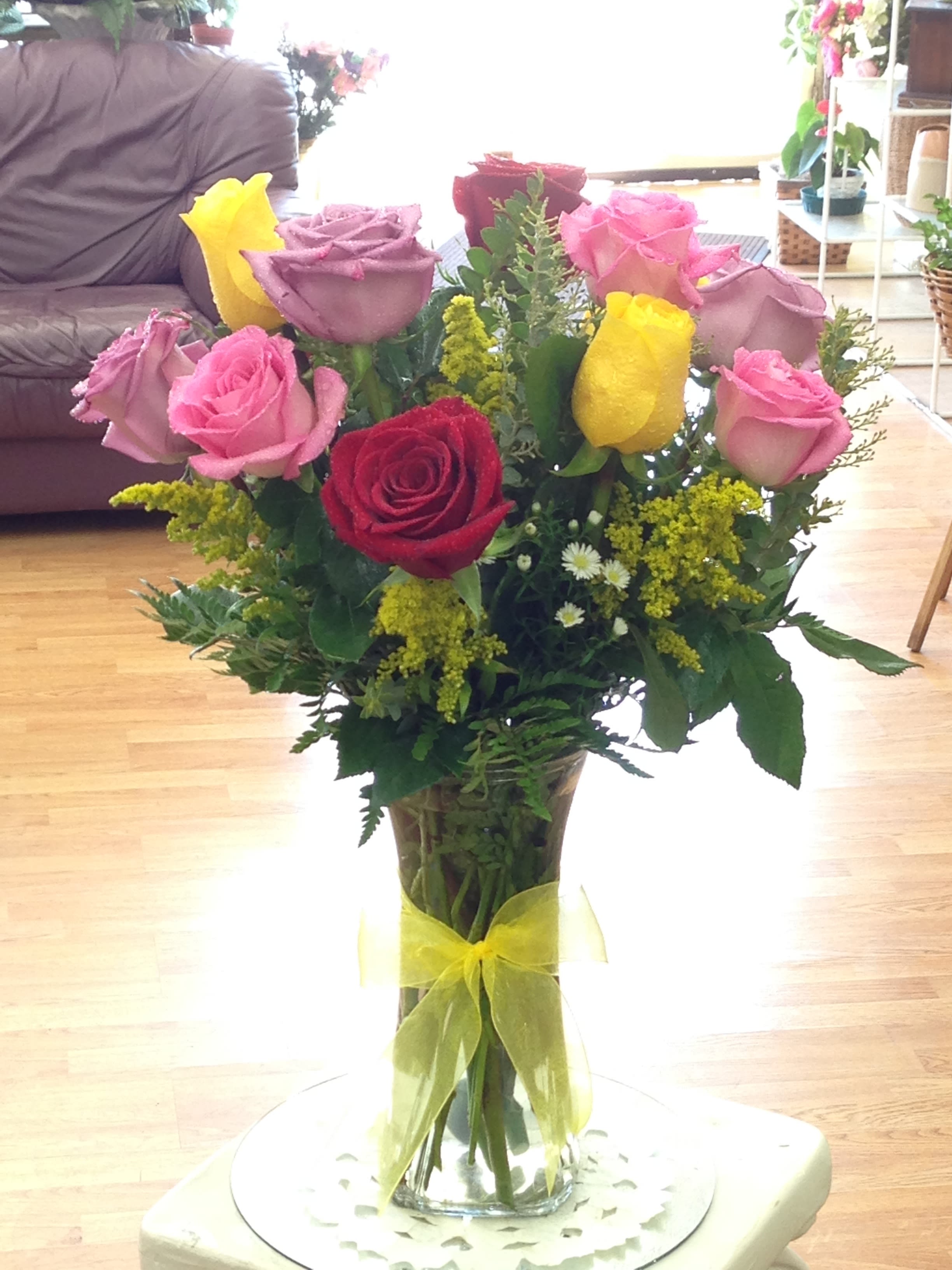 Bouquet of pink, red, and yellow roses in a clear glass vase