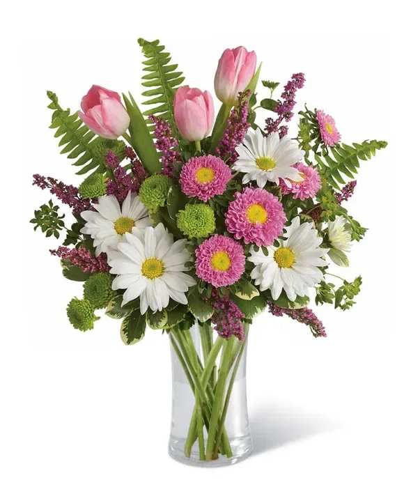 Pink Haze Bouquet - Bright pink tulips set a joyful tone in this Pink Haze bouquet, designed as a springtime birthday bouquet or a cheerful everyday gift. White daisies and small pink-and-green chrysanthemum blooms keep the look light and friendly, while tall fern fronds and purple filler introduce graceful movement that makes the arrangement feel fresh and alive - a lovely way to make someone feel seen and celebrated.  Arranged in a clear glass vase, the composition is airy and rounded with a bright pink, white, green, and purple palette that reads as both casual and thoughtfully styled. The stems are presented at varied heights for texture and visual interest; the vase makes it easy to display on a kitchen table or office desk. Perfect for birthdays, thank-you gestures, or just-because surprises, this bouquet arrives ready to brighten the recipient's day.