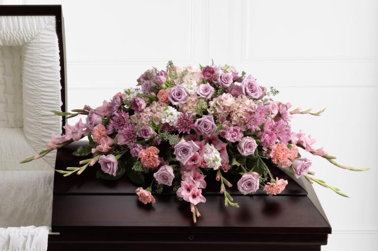 Lavender and pink floral arrangement on a dark casket