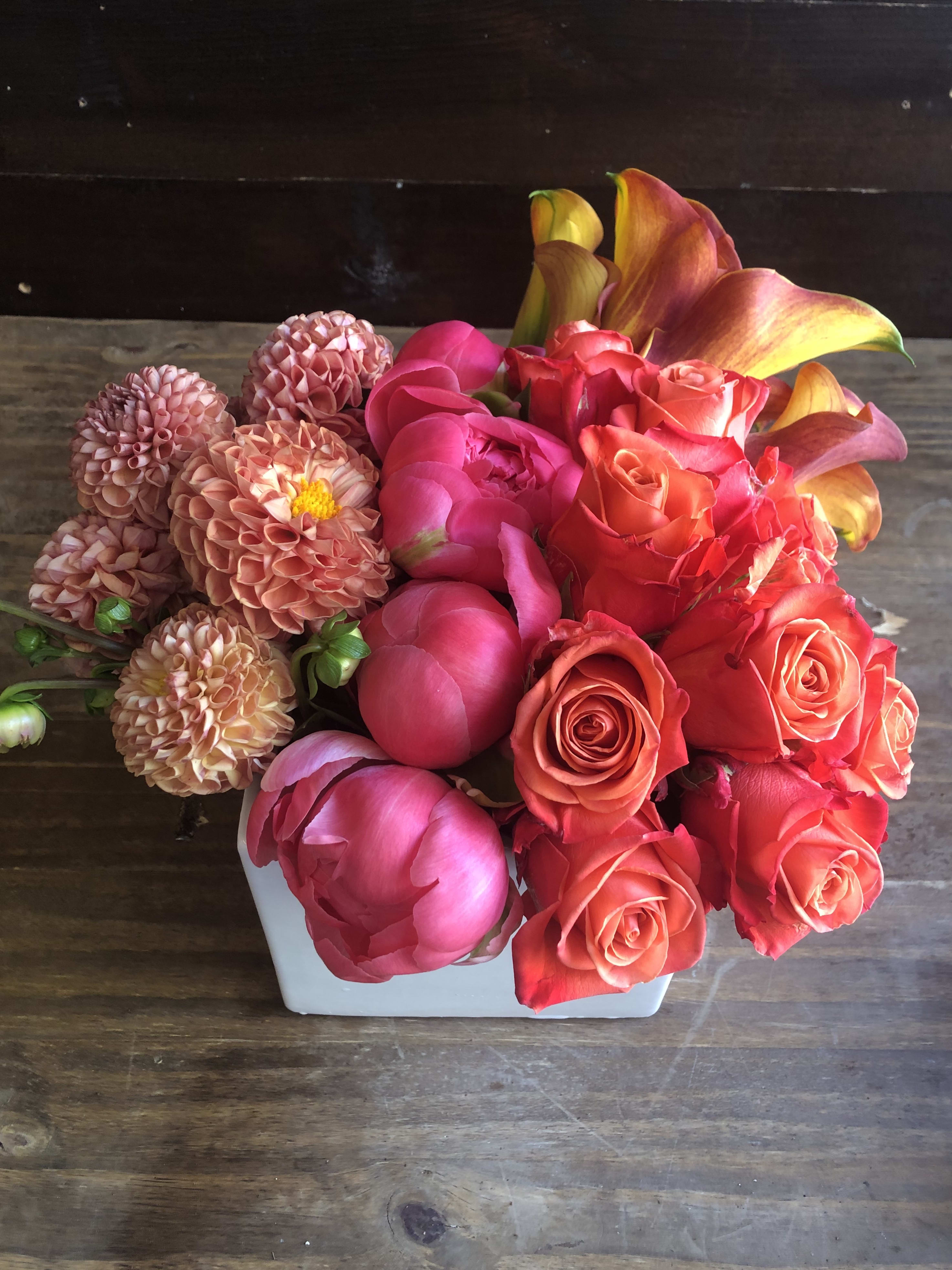 Pink and coral flowers arranged in a white vase