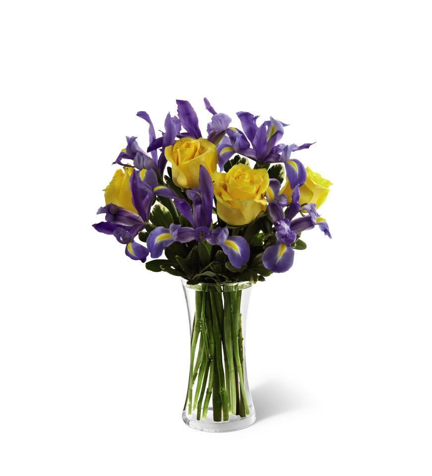 Yellow roses and purple irises in a clear glass vase