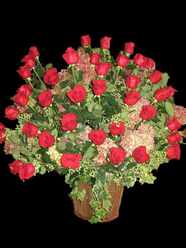 Large arrangement of red roses and pink hydrangeas in a rustic wooden container
