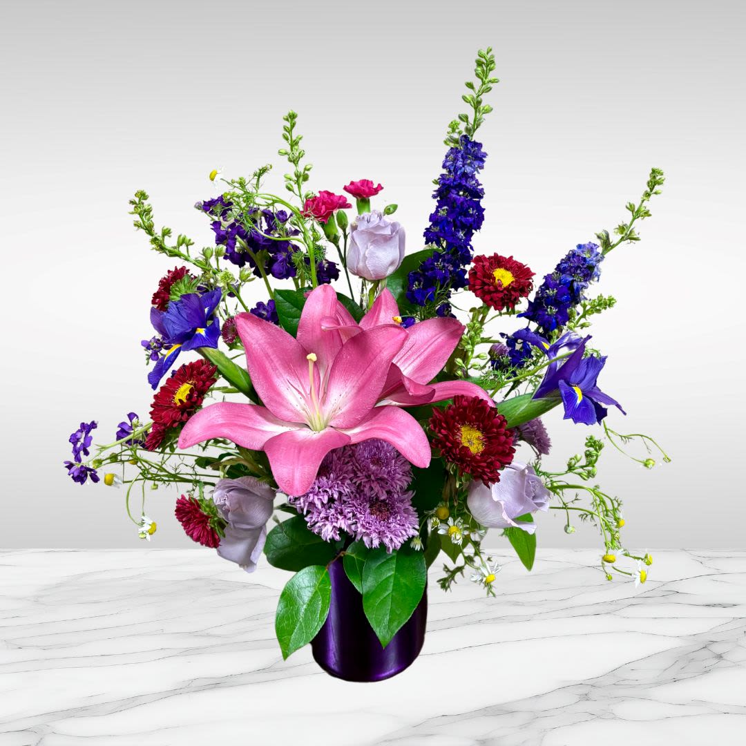 Made to celebrate Mom - This one is made to celebrate Mother's Day with bright purples and pinks! Recipe: Larkspur, Lavender Roses, Pink Lilies, Matsumoto, Mini Carnations, and Chrysanthemums Seasonal: All year round Orientation: Front Facing View Photo shown: Standard  