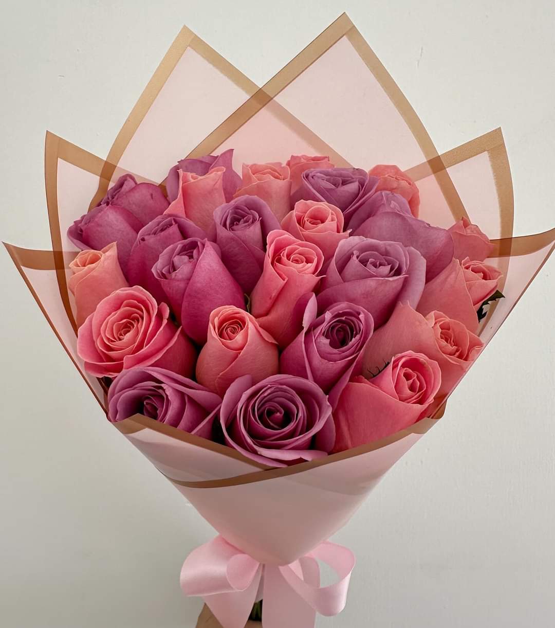 Bouquet of pink and purple roses wrapped in pink paper with a ribbon