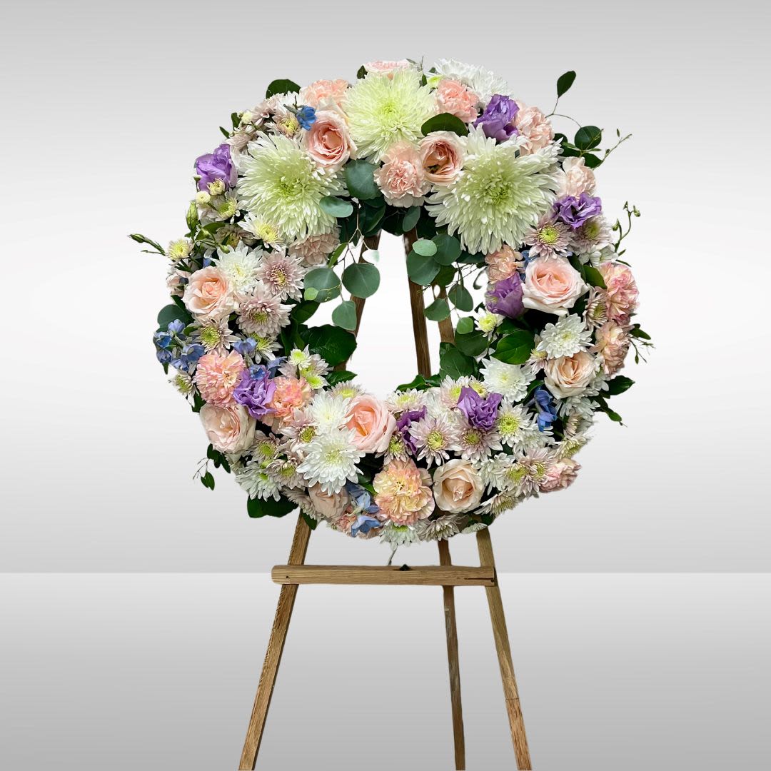 Soft and Sweet Wreath (displaying premium) - Recipe: Mix of roses, lisianthus, carnations, fuji mums, delphinium on a circle wreath easle. Seasonal: All year round Orientation: Front Facing View Photo shown: Premium