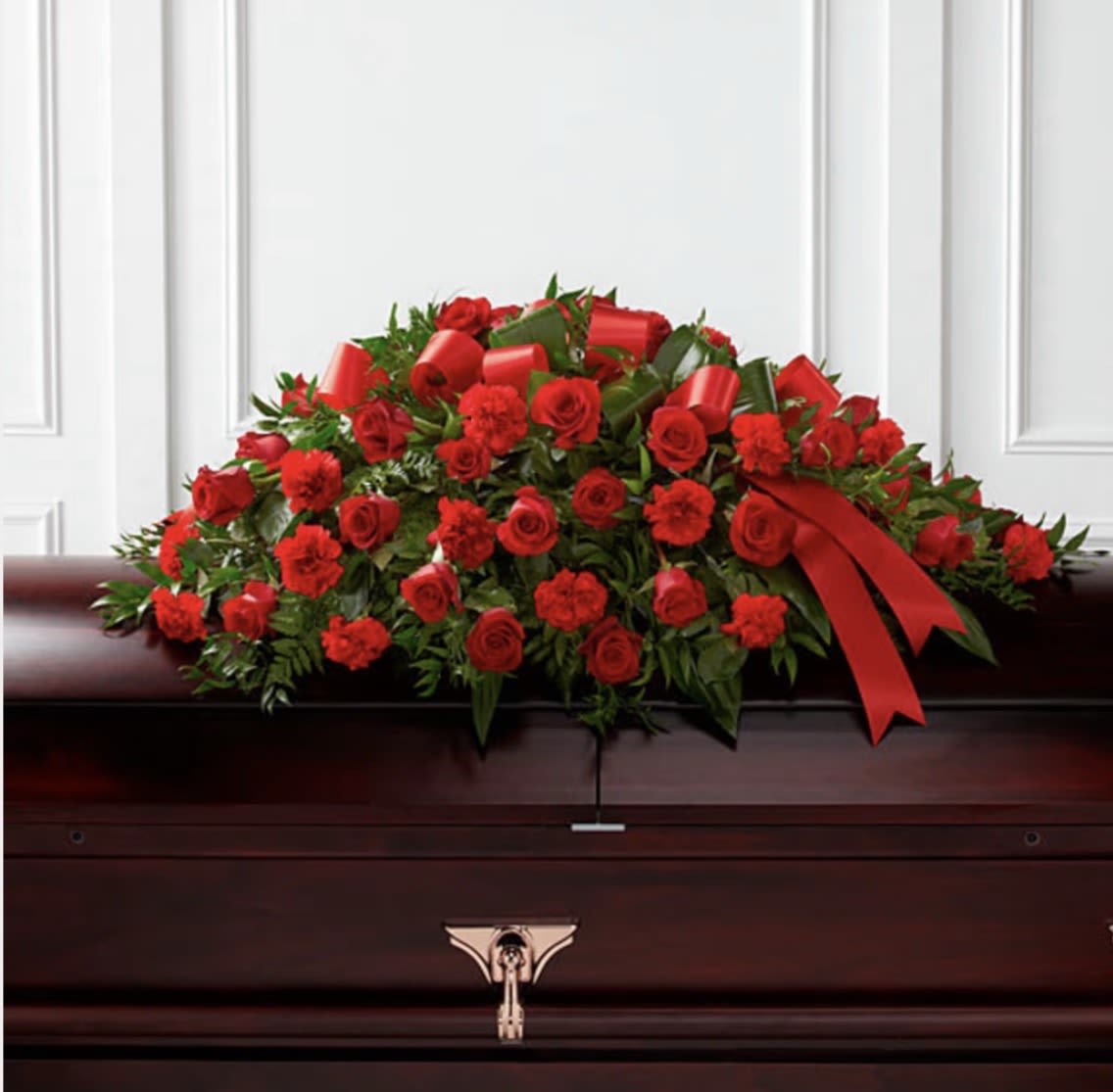 DEARLY DEPARTED CASKET SPRAY - A graceful and deeply meaningful tribute, this casket spray of red roses symbolizes enduring love, respect, and remembrance. Lush, velvety red blooms are carefully arranged to flow elegantly across the casket, creating a striking display of beauty and serenity. Accented with rich greenery, the roses convey heartfelt emotions—love that transcends time, courage, and profound admiration. This classic arrangement offers a powerful expression of devotion and serves as a dignified farewell to someone dearly cherished.