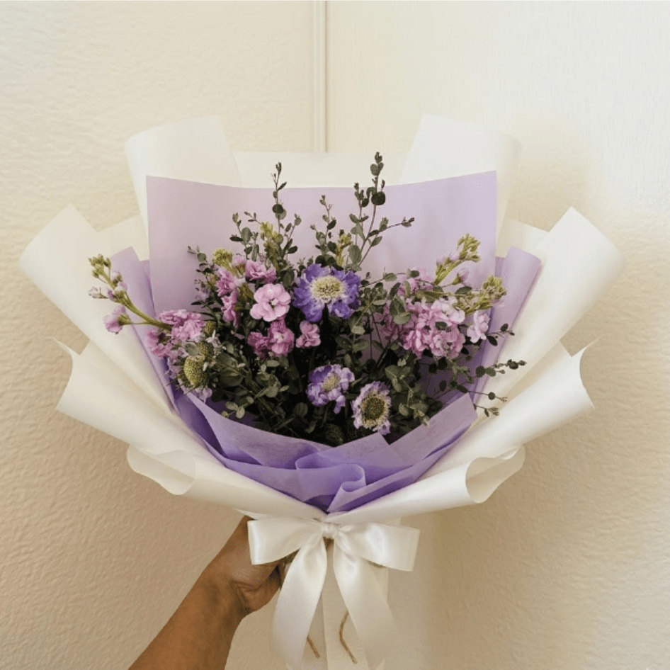 Twilight Mist - Moody, elegant, and mysterious—Twilight Mist captures the sophisticated beauty of the evening hour. Deep purples are softened by the silvery tones of eucalyptus, making this the perfect choice for an anniversary dinner under the stars.  This seasonal bouquet features:  Lavender Stock  Purple Scabiosa  Silvery Gunni Eucalyptus  Garden Greens  Presentation: Expertly wrapped in our signature textured paper and tied with satin ribbon. Prefer a vase? Add one to your cart to complete the look.  Personal Touch: We’ll include a custom card message with every order. You’ll be able to write your message at checkout.  Please Note: All flowers are subject to seasonal availability. If a specific bloom isn’t available, our designers will thoughtfully substitute with flowers in a similar shape, style, and color.  Standard size shown. Vase upgrade is optional.   Floral Care Guide  Your arrangement arrives in our signature "double wrap" and is nestled in a protective box. While the stems are secured with a wet wrap for transit they are ready for a full drink!   Unpack: Gently lift the bouquet from the box. Remove the plastic bag and wet towel from the stems. Trim &amp; Hydrate: Trim 1/2" off stems at an angle and place in a clean vase with cool water. Refreshed: Change water daily for a long-lasting bloom.  