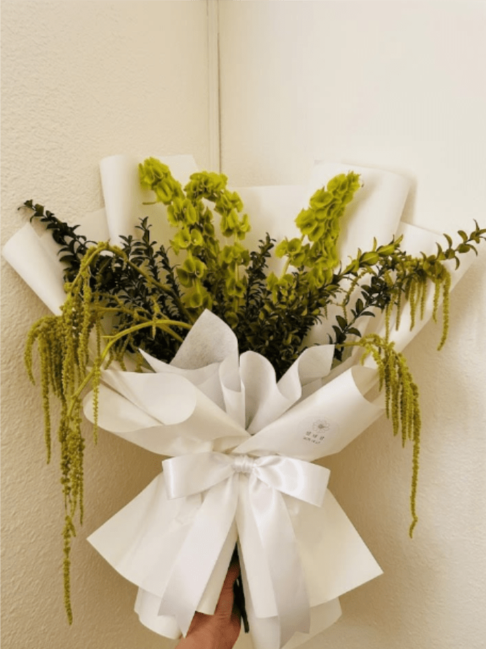 Emerald Rest - Architectural, lush, and peaceful—Emerald Rest is a unique alternative to traditional sympathy arrangements. All-green textures of bells of Ireland and trailing amaranthus create a forest-like feel that represents eternal life.  This seasonal bouquet features:  Bells of Ireland  Green Hanging Amaranthus  Fresh Boxwood  Garden Greens  Presentation: Expertly wrapped in our signature textured paper and tied with satin ribbon. Prefer a vase? Add one to your cart to complete the look.  Personal Touch: We’ll include a custom card message with every order. You’ll be able to write your message at checkout.  Please Note: All flowers are subject to seasonal availability. If a specific bloom isn’t available, our designers will thoughtfully substitute with flowers in a similar shape, style, and color.  Standard size shown. Vase upgrade is optional.   Floral Care Guide  Your arrangement arrives in our signature "double wrap" and is nestled in a protective box. While the stems are secured with a wet wrap for transit they are ready for a full drink!   Unpack: Gently lift the bouquet from the box. Remove the plastic bag and wet towel from the stems. Trim &amp; Hydrate: Trim 1/2" off stems at an angle and place in a clean vase with cool water. Refreshed: Change water daily for a long-lasting bloom.  