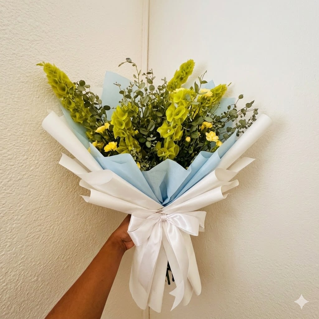 Heavenly Bells - Upward-reaching, noble, and hopeful—Heavenly Bells is a timeless tribute to a life in transition. This clean white and green palette fits seamlessly into any memorial setting, offering a sense of peace and honor.  This seasonal bouquet features:  Yellow Carnations  Bells of Ireland  Fresh Boxwood  Garden Greens  Presentation: Expertly wrapped in our signature textured paper and tied with satin ribbon. Prefer a vase? Add one to your cart to complete the look.  Personal Touch: We’ll include a custom card message with every order. You’ll be able to write your message at checkout.  Please Note: All flowers are subject to seasonal availability. If a specific bloom isn’t available, our designers will thoughtfully substitute with flowers in a similar shape, style, and color.  Standard size shown. Vase upgrade is optional.   Floral Care Guide  Your arrangement arrives in our signature "double wrap" and is nestled in a protective box. While the stems are secured with a wet wrap for transit they are ready for a full drink!   Unpack: Gently lift the bouquet from the box. Remove the plastic bag and wet towel from the stems. Trim &amp; Hydrate: Trim 1/2" off stems at an angle and place in a clean vase with cool water. Refreshed: Change water daily for a long-lasting bloom. 