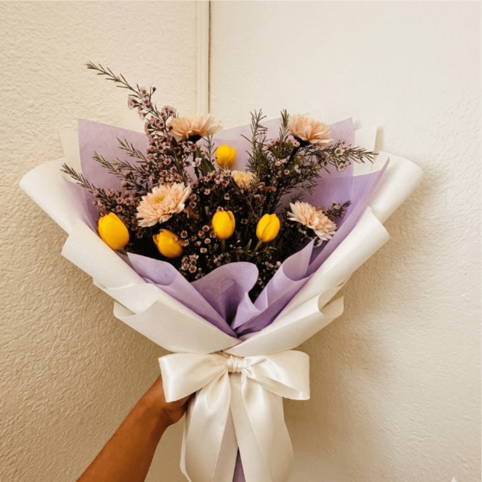 Cheerful Soul - Warm, friendly, and optimistic—Cheerful Soul is a sunny reminder that better days are ahead. The combination of peach mums and vibrant tulips provides a sense of comfort and a bright outlook.  This seasonal bouquet features:  Peach Mums  Yellow Tulips  Starry Pink Waxflower  Garden Greens  Presentation: Expertly wrapped in our signature textured paper and tied with satin ribbon. Prefer a vase? Add one to your cart to complete the look.  Personal Touch: We’ll include a custom card message with every order. You’ll be able to write your message at checkout.  Please Note: All flowers are subject to seasonal availability. If a specific bloom isn’t available, our designers will thoughtfully substitute with flowers in a similar shape, style, and color.  Standard size shown. Vase upgrade is optional.   Floral Care Guide  Your arrangement arrives in our signature "double wrap" and is nestled in a protective box. While the stems are secured with a wet wrap for transit they are ready for a full drink!   Unpack: Gently lift the bouquet from the box. Remove the plastic bag and wet towel from the stems. Trim &amp; Hydrate: Trim 1/2" off stems at an angle and place in a clean vase with cool water. Refreshed: Change water daily for a long-lasting bloom.  