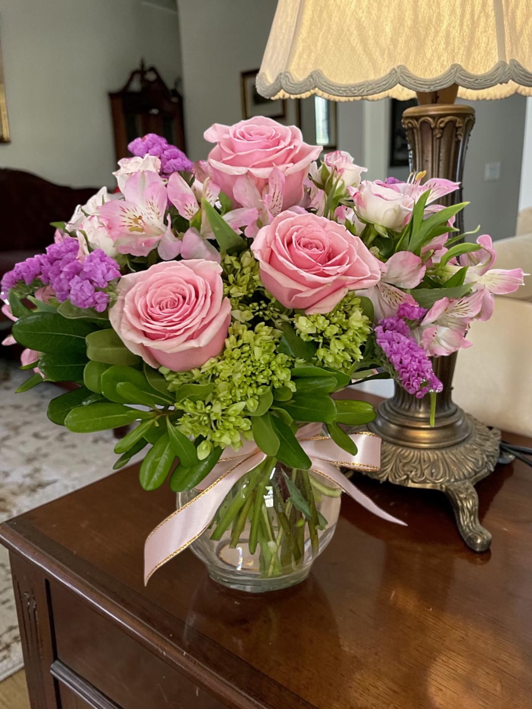 Rosy Charm - Brighten someone’s day with Rosy Charm, a soft and cheerful fresh flower arrangement featuring pink roses, pink spray roses, alstroemeria, green hydrangea, lavender statice, and lush greenery designed in a clear glass bubble bowl. Finished with ribbon accents, this charming bouquet offers a fresh, elegant look that feels warm and thoughtful.  Rosy Charm is a beautiful gift for birthdays, Mother’s Day, new baby celebrations, love and romance, thank you gifts, or just because. Its soft pink tones and garden-fresh texture make it a lovely choice when you want to send something sweet, stylish, and uplifting.  Each arrangement is professionally handcrafted by Aspen Tower Florist using fresh flowers and quality design materials. Flower varieties or shades may vary slightly based on seasonal availability while maintaining the overall style, color palette, and value.  We proudly offer local flower delivery in Greensburg, Indiana, and surrounding communities including Rushville, Batesville, Shelbyville, North Vernon, Hope, Westport, and nearby areas.  Order Rosy Charm today from Aspen Tower Florist for a gift that feels personal, beautiful, and memorable. Perfect for sending love, celebrating life’s moments, or simply making someone smile.