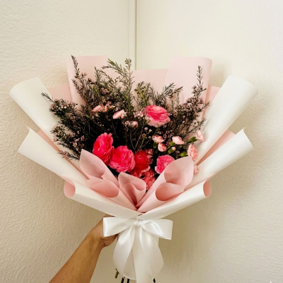 Pink Champagne - Chic, bubbly, and festive—Pink Champagne is a floral toast to exciting news. Dense, ruffled layers of ranunculus and mini carnations create a luxurious feel that is perfect for a bridal shower or engagement.  This seasonal bouquet features:  Hot Pink Ranunculus  Light Pink Mini Carnations  Starry Pink Waxflower  Garden Greens  Presentation: Expertly wrapped in our signature textured paper and tied with satin ribbon. Prefer a vase? Add one to your cart to complete the look.  Personal Touch: We’ll include a custom card message with every order. You’ll be able to write your message at checkout.  Please Note: All flowers are subject to seasonal availability. If a specific bloom isn’t available, our designers will thoughtfully substitute with flowers in a similar shape, style, and color.  Standard size shown. Vase upgrade is optional.   Floral Care Guide  Your arrangement arrives in our signature "double wrap" and is nestled in a protective box. While the stems are secured with a wet wrap for transit they are ready for a full drink!   Unpack: Gently lift the bouquet from the box. Remove the plastic bag and wet towel from the stems. Trim &amp; Hydrate: Trim 1/2" off stems at an angle and place in a clean vase with cool water. Refreshed: Change water daily for a long-lasting bloom. 