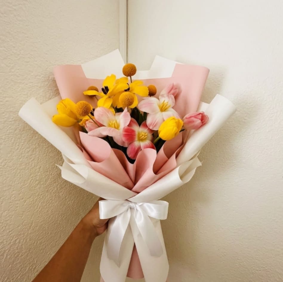 High Five - Fun, bright, and energetic—High Five is a literal celebration of a job well done. Playful yellow billy buttons and vibrant tulips create a modern, joyful mix that is guaranteed to keep the celebratory mood going.  This seasonal bouquet features:  Pink Tulips  Yellow Tulips  Yellow Billy Buttons  Garden Greens  Presentation: Expertly wrapped in our signature textured paper and tied with satin ribbon. Prefer a vase? Add one to your cart to complete the look.  Personal Touch: We’ll include a custom card message with every order. You’ll be able to write your message at checkout.  Please Note: All flowers are subject to seasonal availability. If a specific bloom isn’t available, our designers will thoughtfully substitute with flowers in a similar shape, style, and color.  Standard size shown. Vase upgrade is optional.   Floral Care Guide  Your arrangement arrives in our signature "double wrap" and is nestled in a protective box. While the stems are secured with a wet wrap for transit they are ready for a full drink!   Unpack: Gently lift the bouquet from the box. Remove the plastic bag and wet towel from the stems. Trim &amp; Hydrate: Trim 1/2" off stems at an angle and place in a clean vase with cool water. Refreshed: Change water daily for a long-lasting bloom.  
