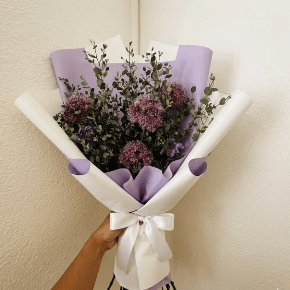 Success Bloom - Artistic, modern, and striking—Success Bloom symbolizes unique achievement. The architectural beauty of allium and purple scabiosa creates a design-forward look for the ambitious individual who has reached their goal.  This seasonal bouquet features:  Purple Allium  Lavender Scabiosa  Silvery Gunni Eucalyptus  Garden Greens  Presentation: Expertly wrapped in our signature textured paper and tied with satin ribbon. Prefer a vase? Add one to your cart to complete the look.  Personal Touch: We’ll include a custom card message with every order. You’ll be able to write your message at checkout.  Please Note: All flowers are subject to seasonal availability. If a specific bloom isn’t available, our designers will thoughtfully substitute with flowers in a similar shape, style, and color.  Standard size shown. Vase upgrade is optional.   Floral Care Guide  Your arrangement arrives in our signature "double wrap" and is nestled in a protective box. While the stems are secured with a wet wrap for transit they are ready for a full drink!   Unpack: Gently lift the bouquet from the box. Remove the plastic bag and wet towel from the stems. Trim &amp; Hydrate: Trim 1/2" off stems at an angle and place in a clean vase with cool water. Refreshed: Change water daily for a long-lasting bloom.  