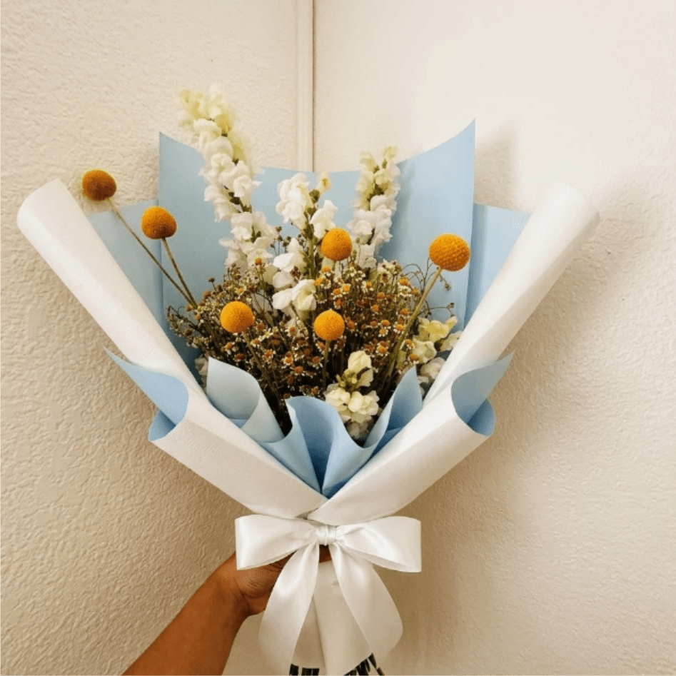 Starlight - Hopeful, modern, and bright—Starlight celebrates the arrival of a new star in the family. Crisp white snapdragons and golden billy buttons bring a bit of magic and cheer to the nursery or living room.  This seasonal bouquet features:  White Snapdragons  Yellow Billy Buttons  Petite White Feverfew  Garden Greens  Presentation: Expertly wrapped in our signature textured paper and tied with satin ribbon. Prefer a vase? Add one to your cart to complete the look.  Personal Touch: We’ll include a custom card message with every order. You’ll be able to write your message at checkout.  Please Note: All flowers are subject to seasonal availability. If a specific bloom isn’t available, our designers will thoughtfully substitute with flowers in a similar shape, style, and color.  Standard size shown. Vase upgrade is optional.   Floral Care Guide  Your arrangement arrives in our signature "double wrap" and is nestled in a protective box. While the stems are secured with a wet wrap for transit they are ready for a full drink!   Unpack: Gently lift the bouquet from the box. Remove the plastic bag and wet towel from the stems. Trim &amp; Hydrate: Trim 1/2" off stems at an angle and place in a clean vase with cool water. Refreshed: Change water daily for a long-lasting bloom.  