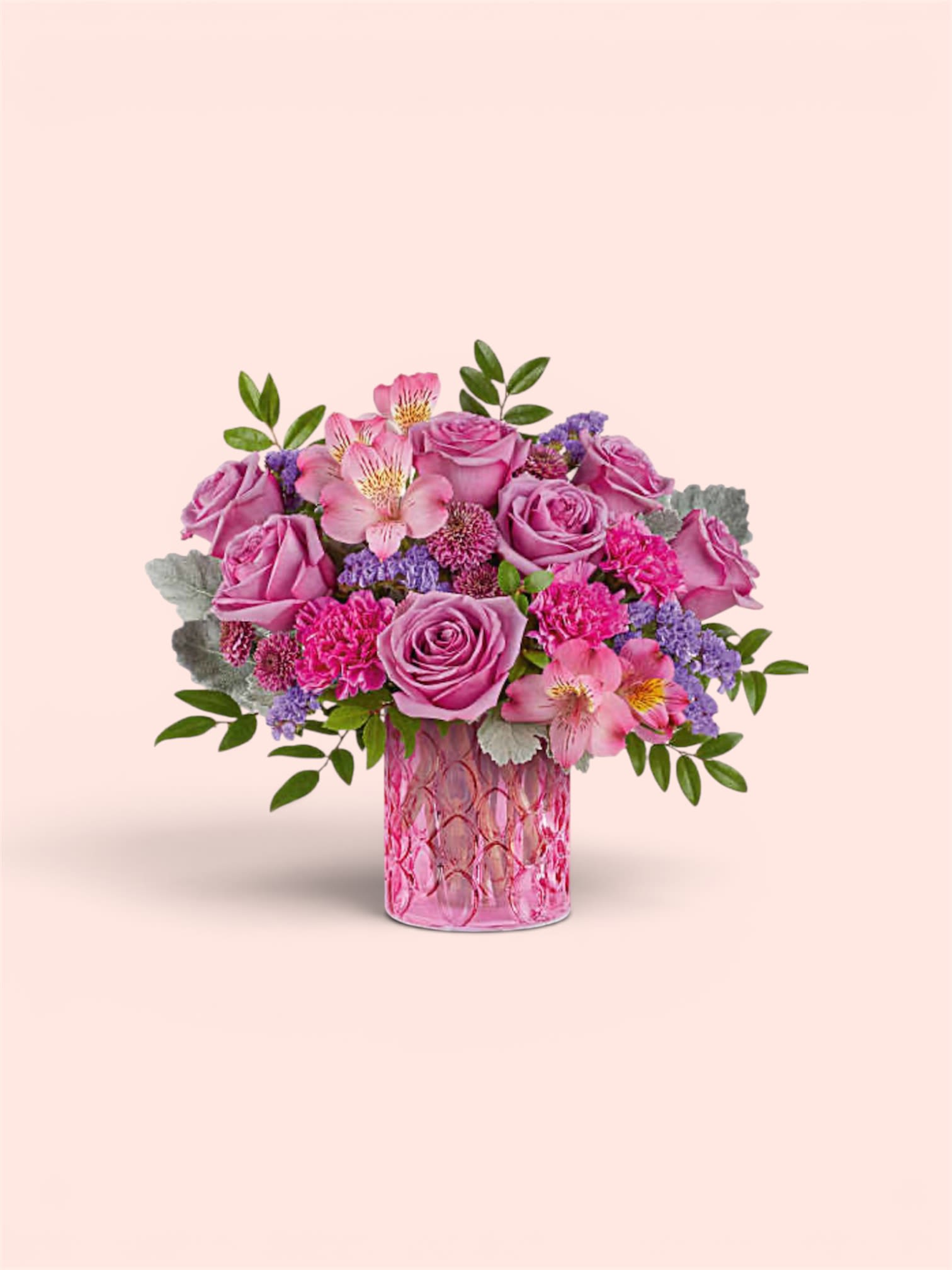 Mother’s Day Special #5 - A lush cluster of pink roses and pink alstroemeria takes center stage in this Mother's Day bouquet, the perfect floral gift for Mother's Day, an anniversary, or to say thank you. The rounded, tightly packed design reads feminine and romantic-she'll feel cherished the moment she sees the soft lavender accents and silvery foliage that catch the light against the textured pink glass vase.  This arrangement pairs bright pink and lavender tones with crisp white and green highlights: pink roses and alstroemeria mingle with small purple filler blooms and delicate silvery leaves for contrast and texture. The flowers are arranged low and full in a textured pink glass vase that enhances the bouquet's cheerful, celebratory mood while keeping stems neatly contained and easy to display.  Ideal for the person you want to make feel truly seen-mom, a grandmother, or a close friend-this arrangement suits birthdays, anniversaries, or "just because" moments when you want to brighten someone's day. Vase-arranged for immediate enjoyment; trim stems and refresh water every few days to extend the life of the blooms.