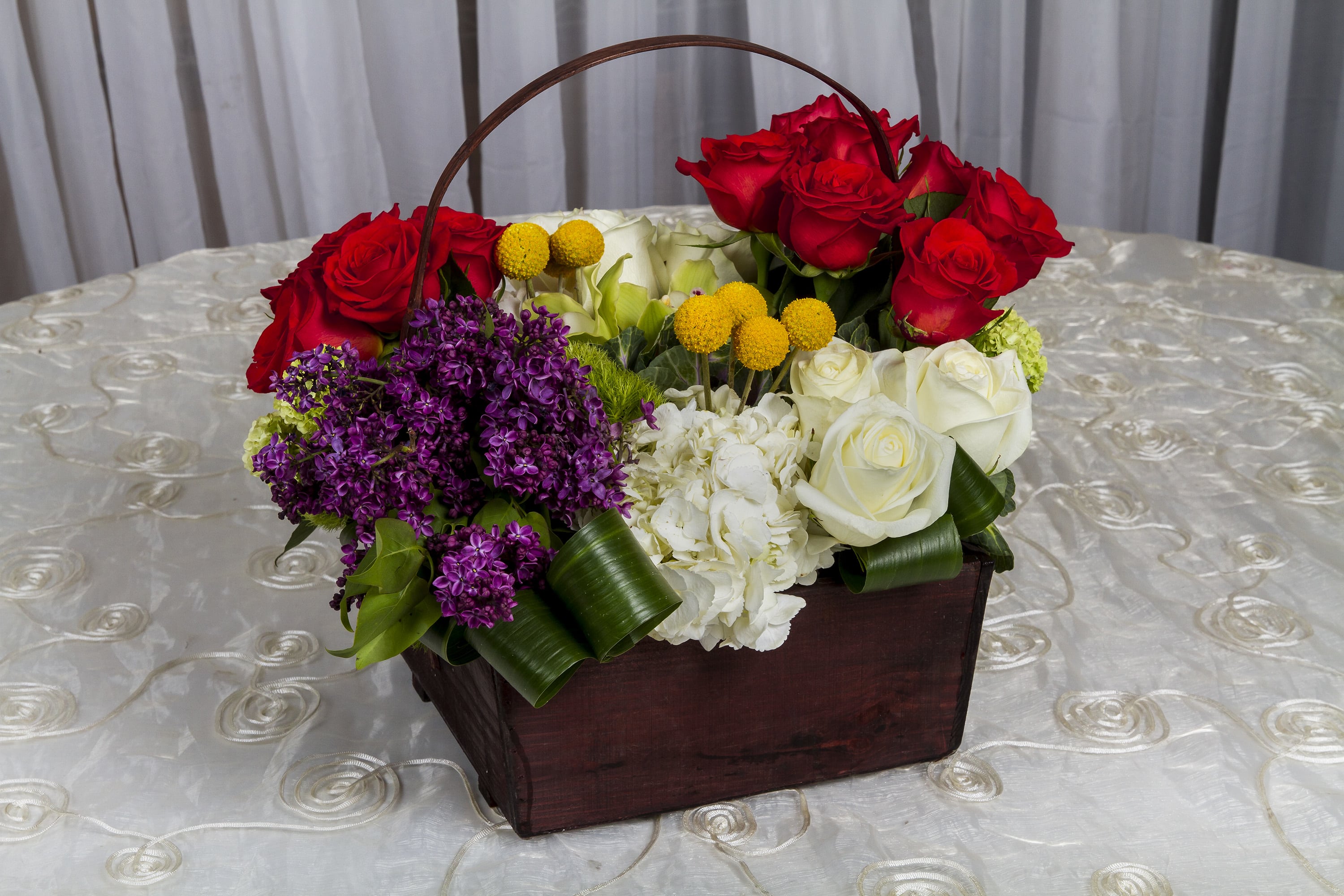 Basket arrangement of red and white roses with purple flowers