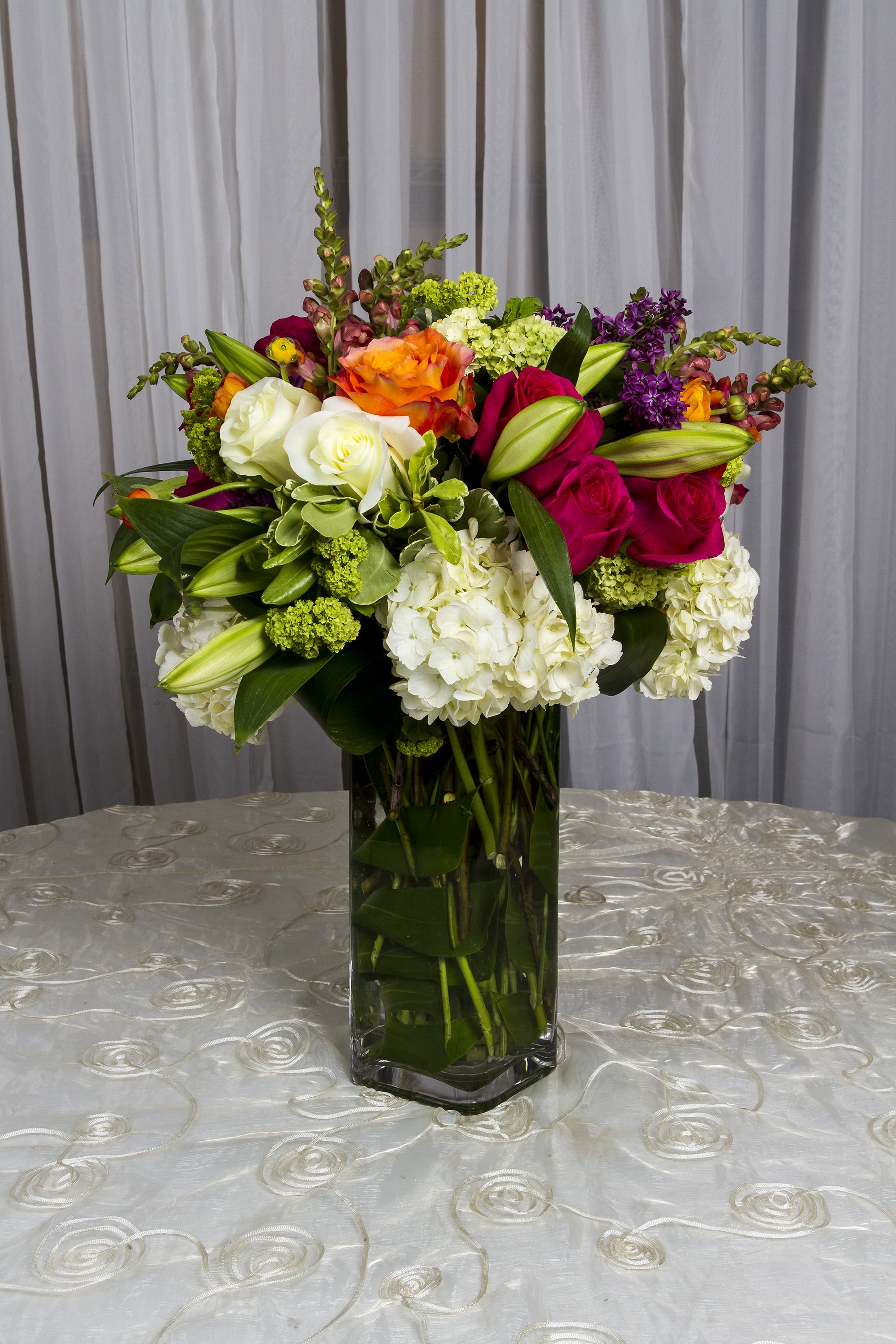 Colorful mixed flower arrangement in a tall glass vase