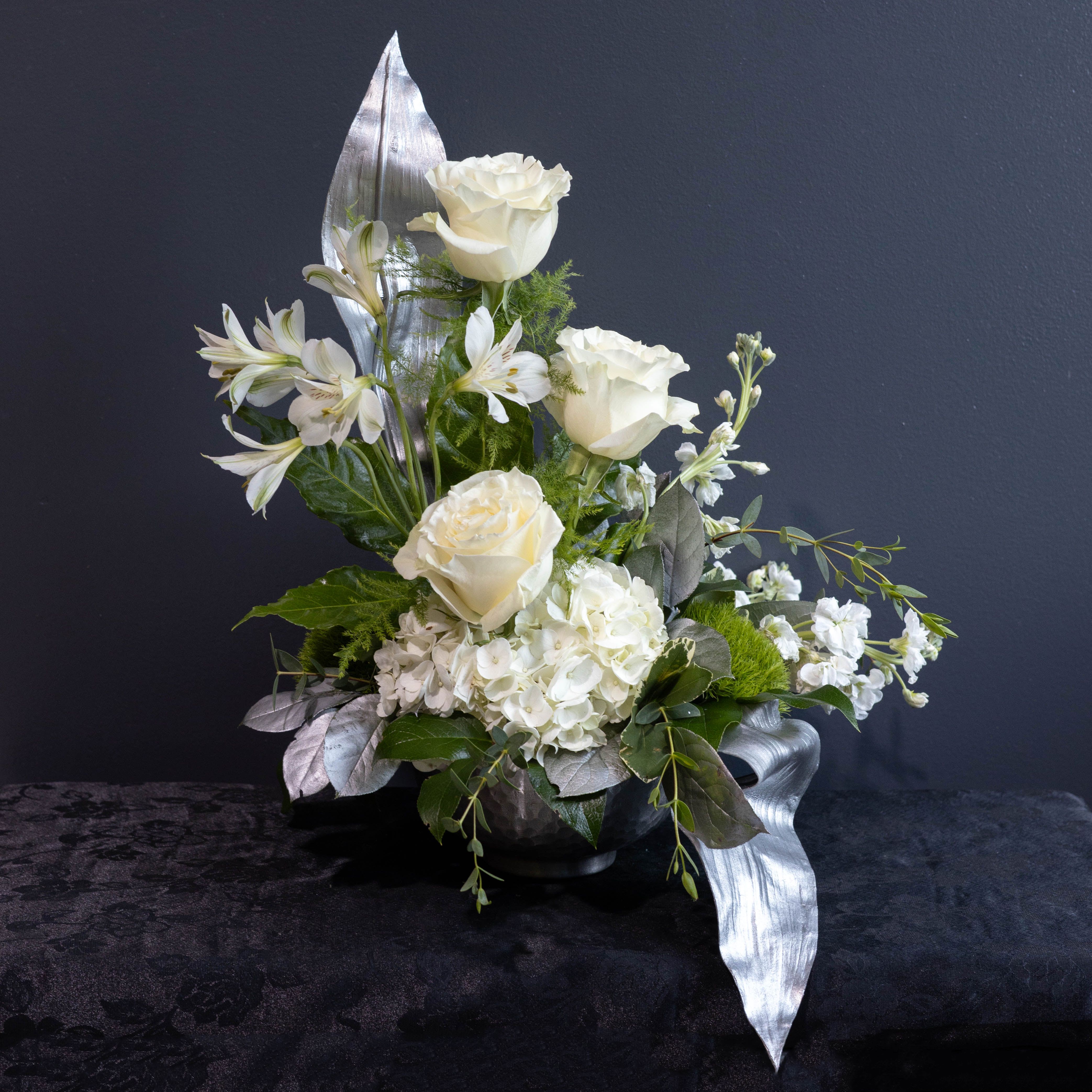 Silver Memories - Elegant, serene, and thoughtfully composed, Silver Memories offers a graceful tribute to honor a life well lived. This refined sympathy arrangement features a harmonious blend of soft white blooms, such as, delicate roses, hydrangea, and accent florals that symbolize peace, remembrance, and enduring love. Perfect for memorial services, funerals, or sending to the home, Silver Memories conveys heartfelt condolences with quiet beauty and sophistication.  A timeless gesture of remembrance, Silver Memories speaks when words are not enough.