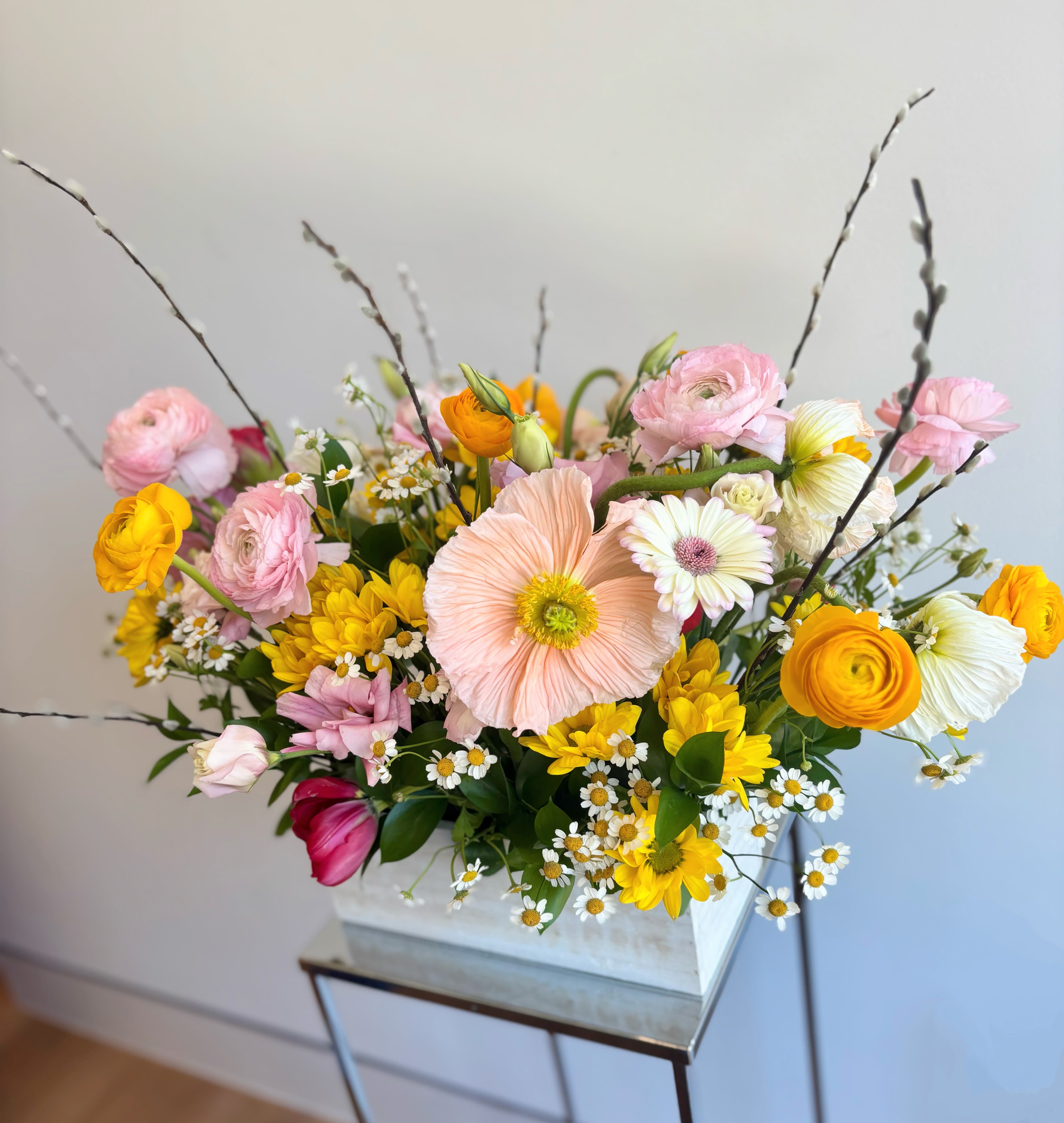 Mixed bouquet in a white rectangular container with pink, yellow, and white blooms