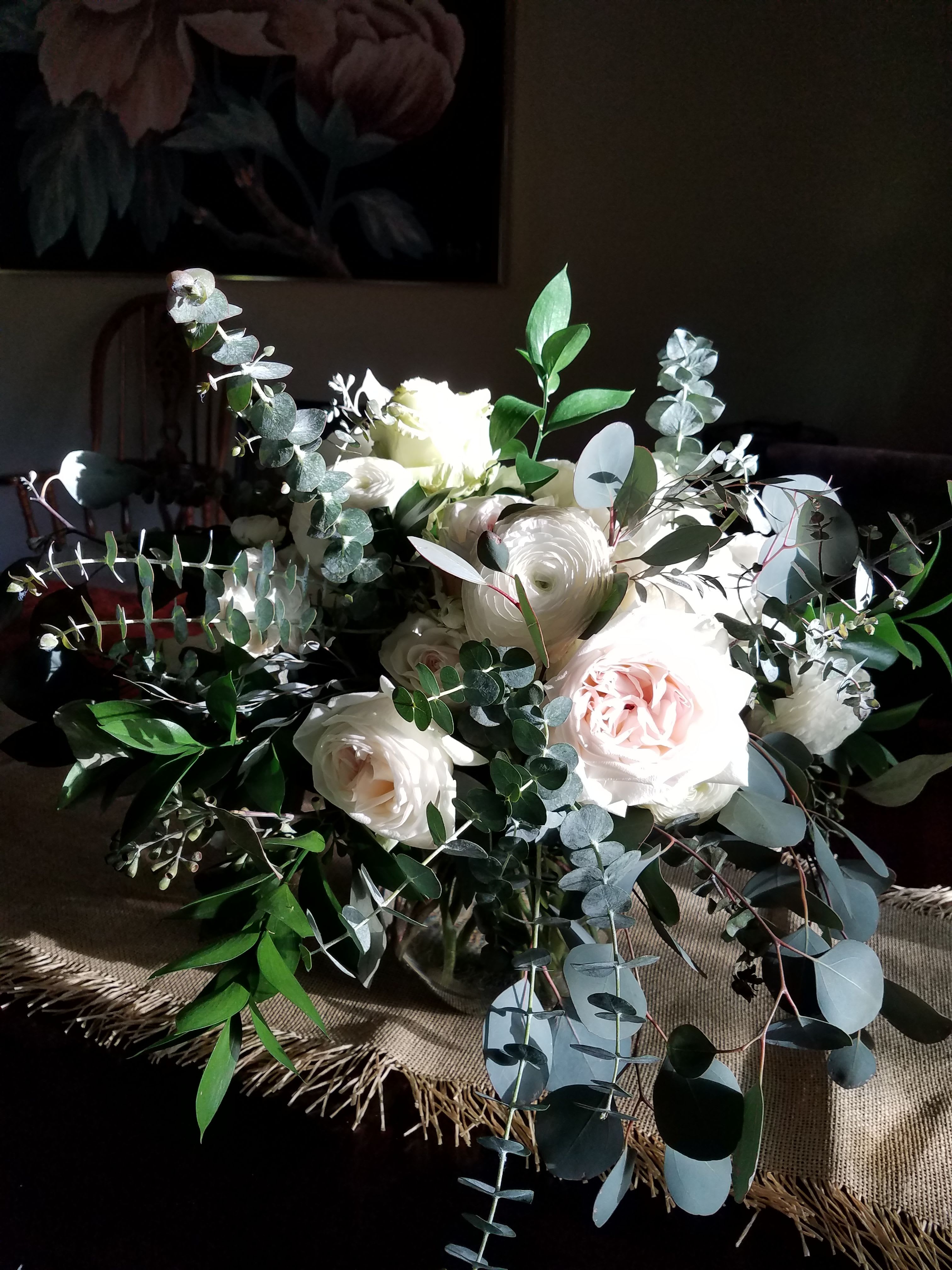 Elegant Garden Table Centerpiece - A romantic garden-style centerpiece featuring soft white and blush blooms accented with lush eucalyptus and seasonal greenery.  Designed to bring a natural, elegant atmosphere to your wedding tables, this arrangement adds texture, softness, and timeless beauty to your event décor. Each piece is handcrafted to create a refined and cohesive look.