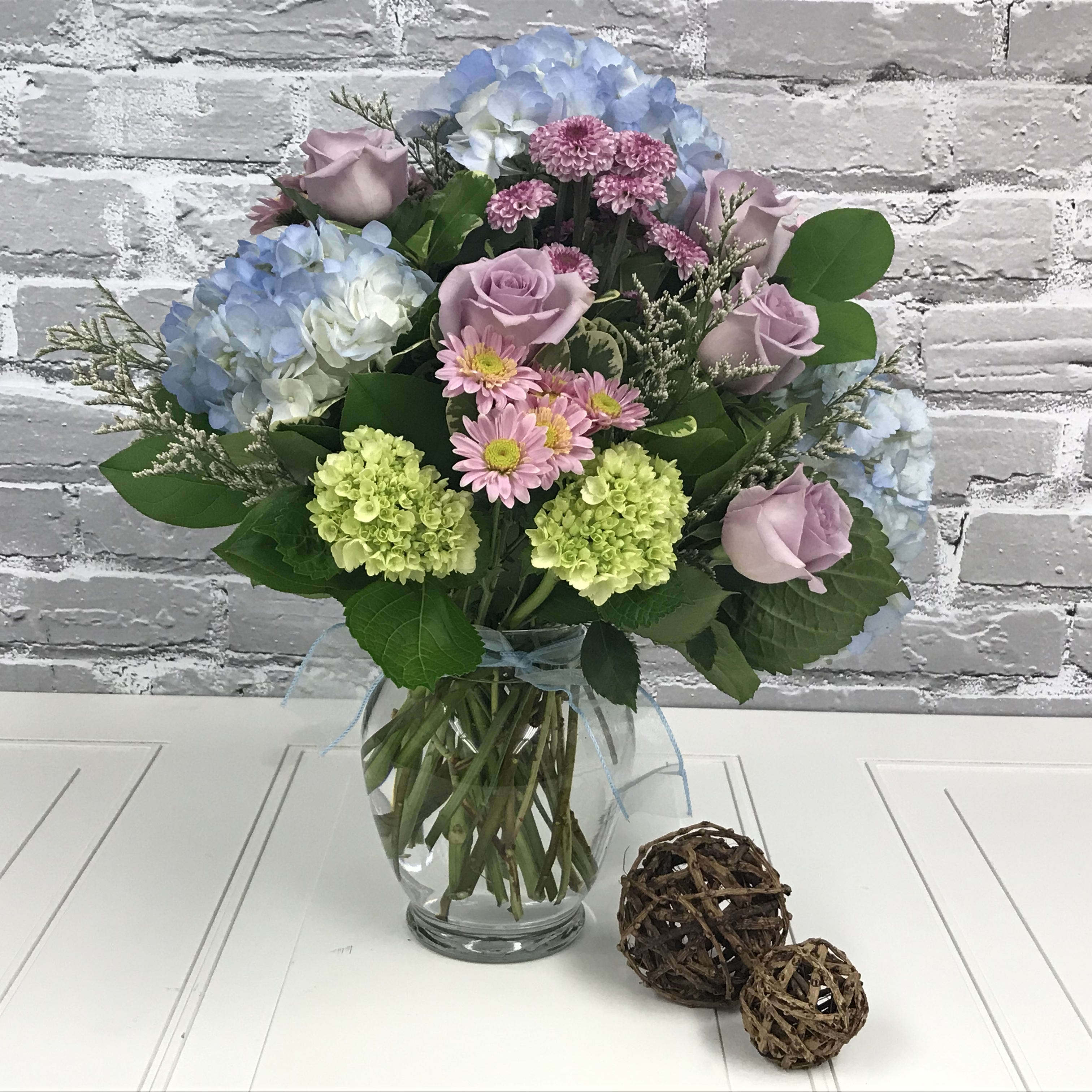Mixed bouquet of pastel flowers in a clear glass vase