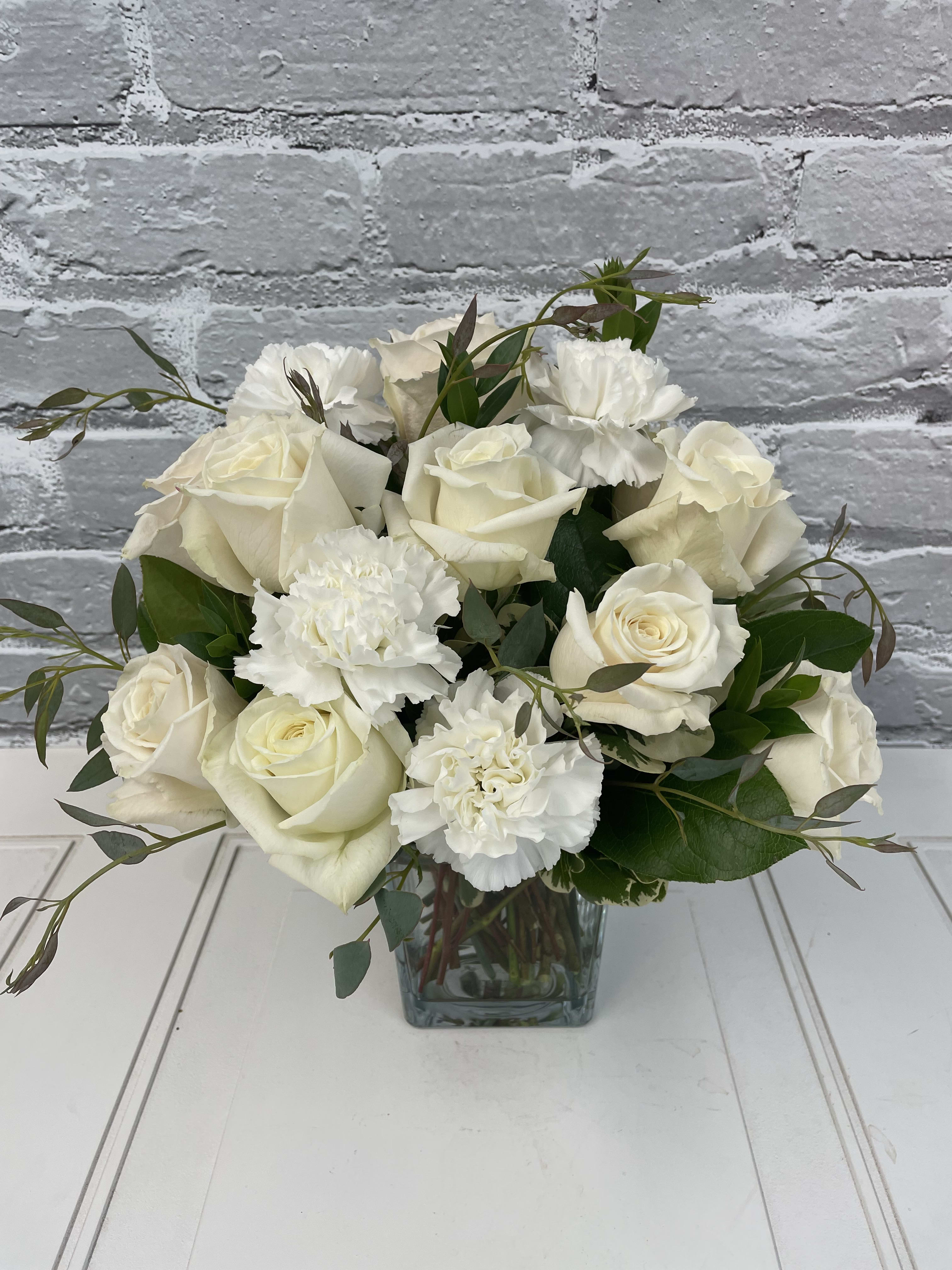 White rose and carnation bouquet in a square glass vase