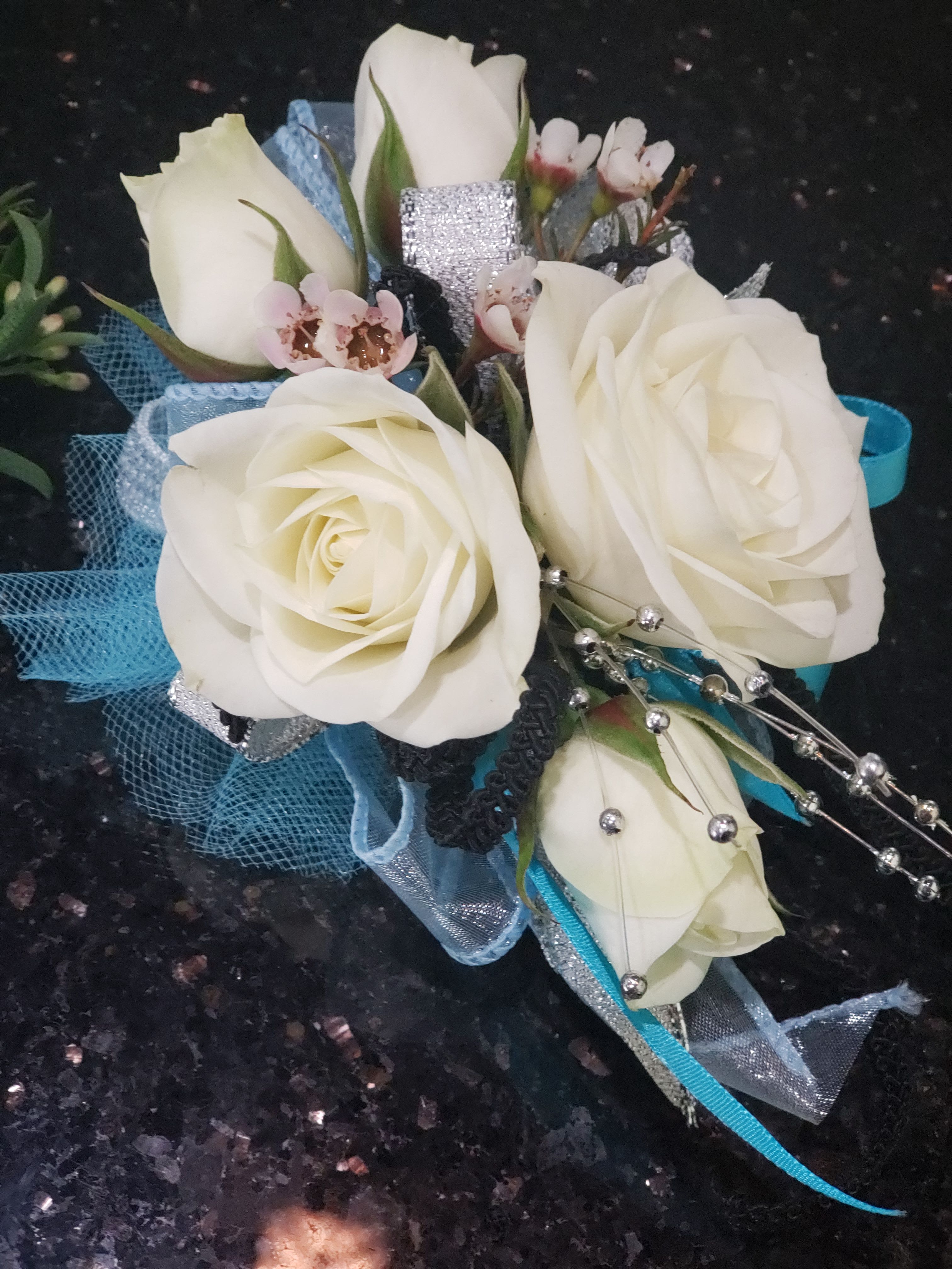 White Rose Wrist Corsage with Ribbon - An elegant wrist corsage featuring classic white roses accented with decorative ribbon and delicate details.  Designed for mothers, bridesmaids, or special guests, this piece adds a refined and graceful touch to any wedding look. Each corsage is handcrafted to complement both classic and modern styles.