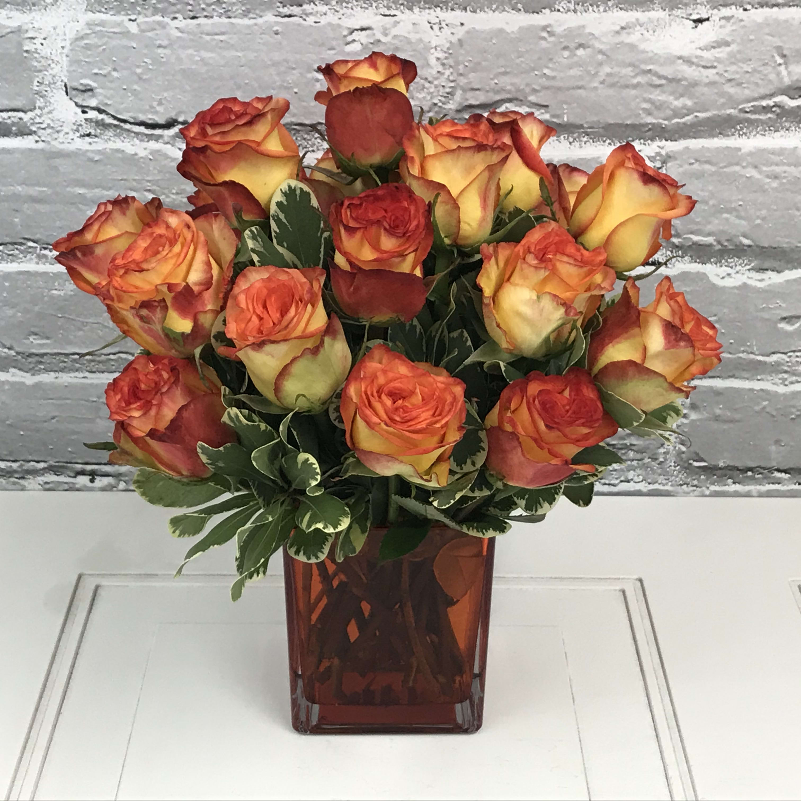 Orange and yellow roses in a red glass vase