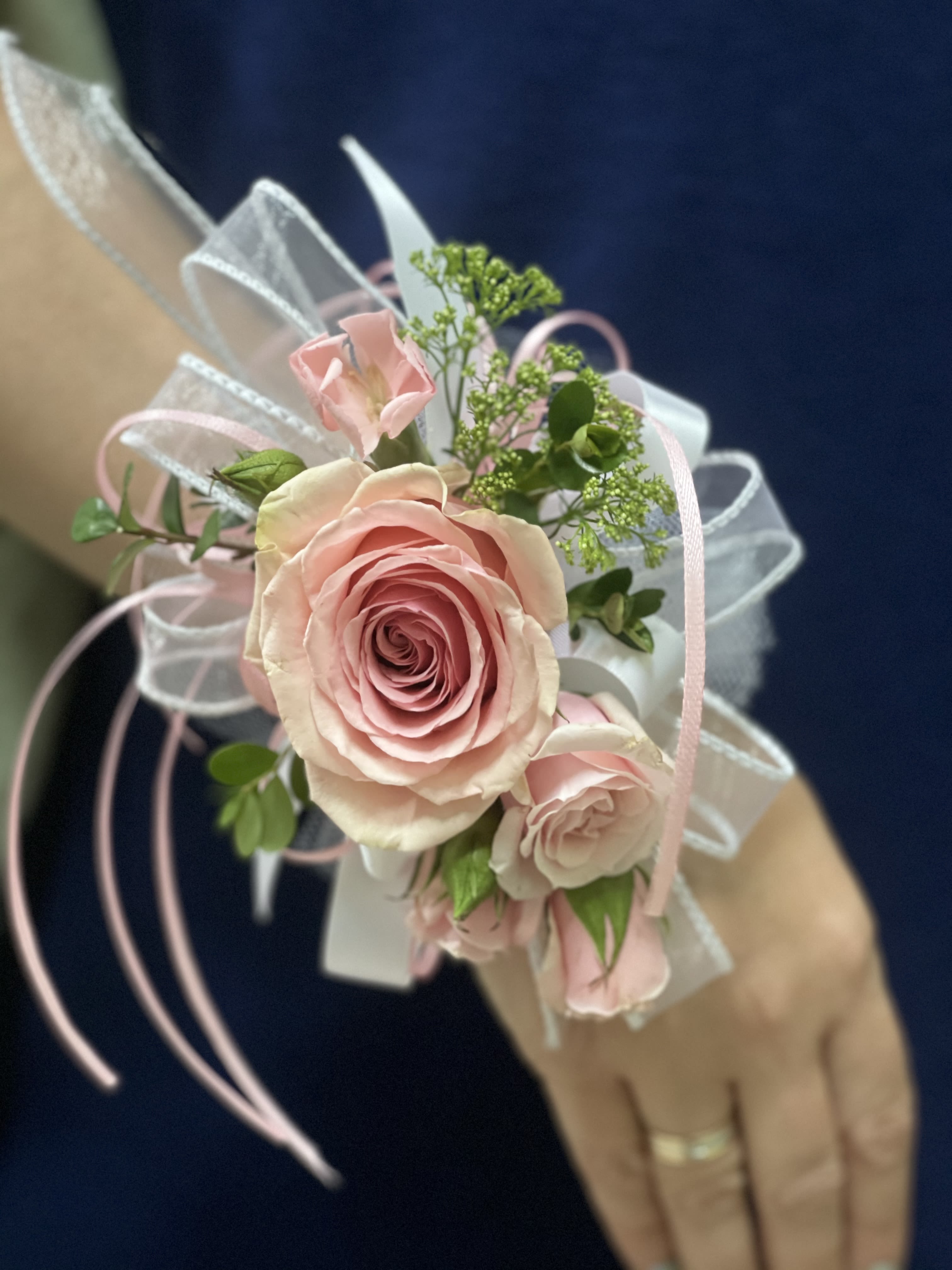 Blush Rose Wrist Corsage - A soft and romantic wrist corsage featuring delicate blush roses, airy greenery, and elegant ribbon accents.  Designed for bridesmaids, mothers, or special guests, this piece adds a feminine and graceful touch to any wedding look. Each corsage is handcrafted to create a light and beautifully balanced floral accessory.