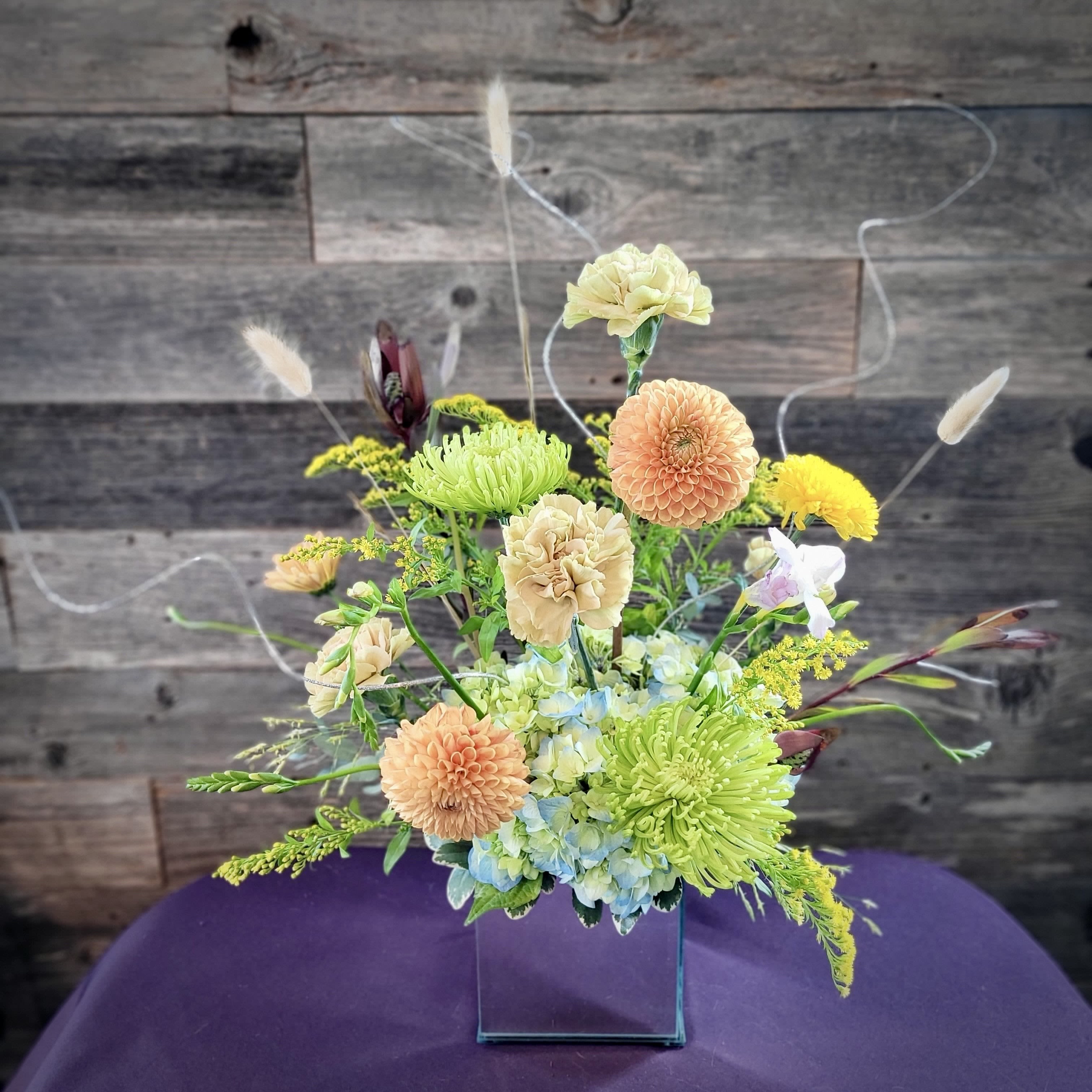 Mixed pastel flower arrangement in a clear square vase