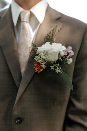 White rose boutonniere on a brown suit jacket