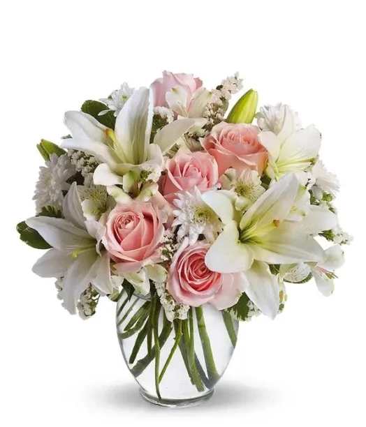 Pink roses and white lilies arranged in a clear glass vase