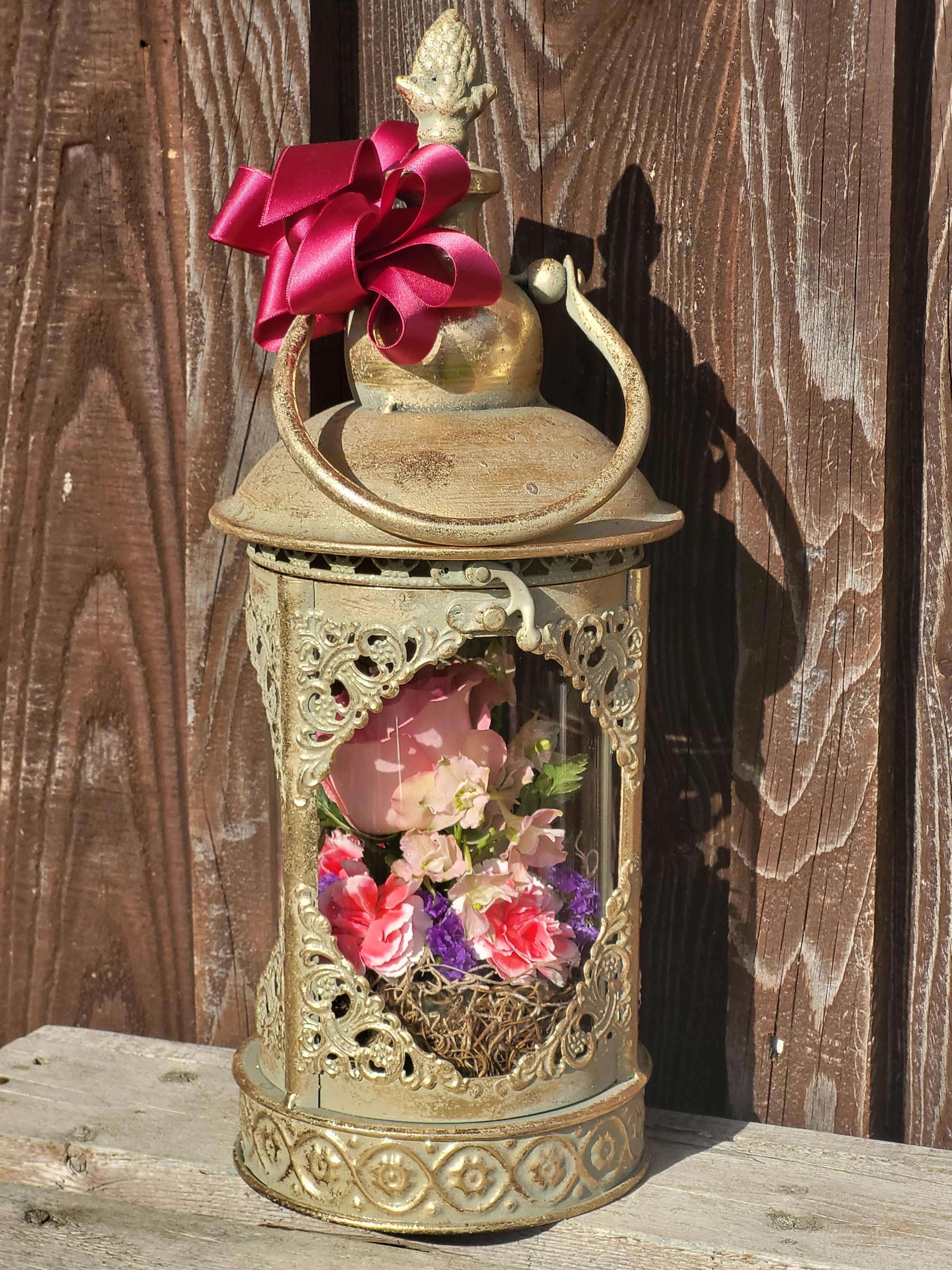 Decorative lantern with pink and purple flowers inside and a magenta ribbon bow on top