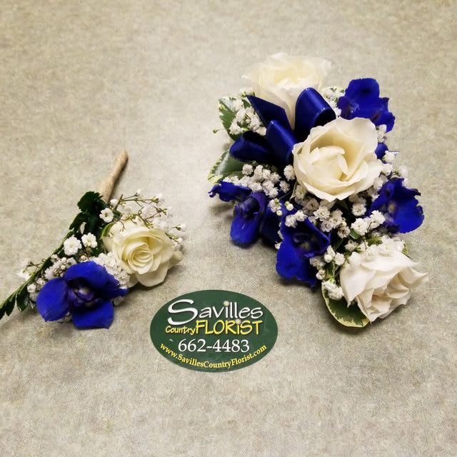Two blue and white floral corsages with roses and baby's breath.