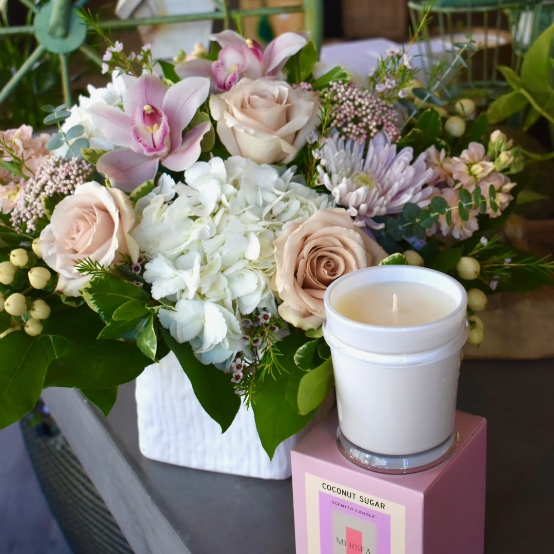 She Deserves All The Love Gift Bundle - A cascade of timeless blush hues, She Deserves All The Love contains white hydrangea, quicksand roses, pink orchids, pink fairytale cremons, peach stock, pink rice flower, pink wax flower, and white hypericum in a linen cube. We've paired it with the Mersea Cabana Flower Candle - Hand-poured &amp; made of a high-quality soy wax blend with an approximate burn time of 70 hours, this exotic fragrance boasts notes of mint, salt flower and ylang ylang.