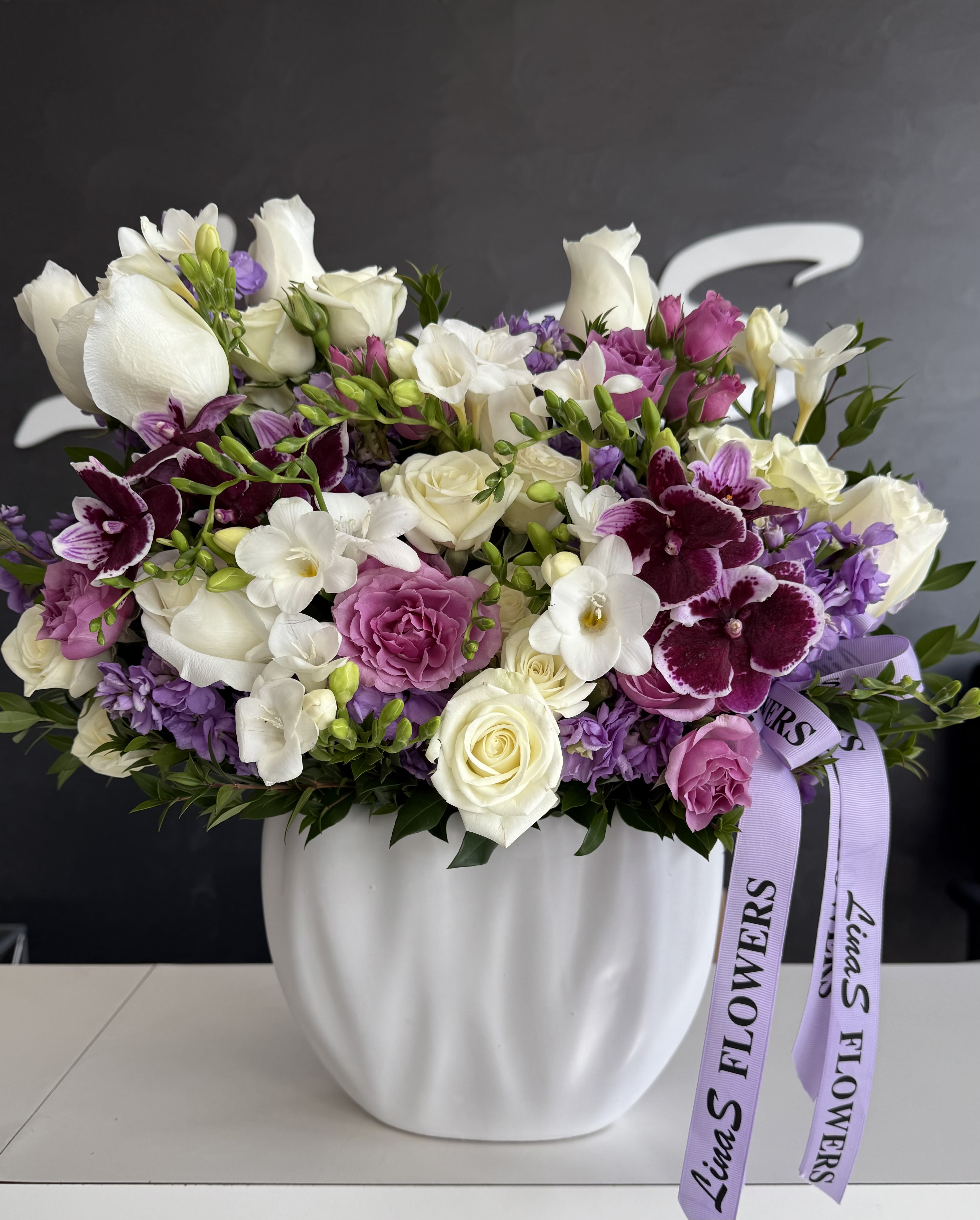 Lavender and white mixed bouquet in a white vase with ribbon