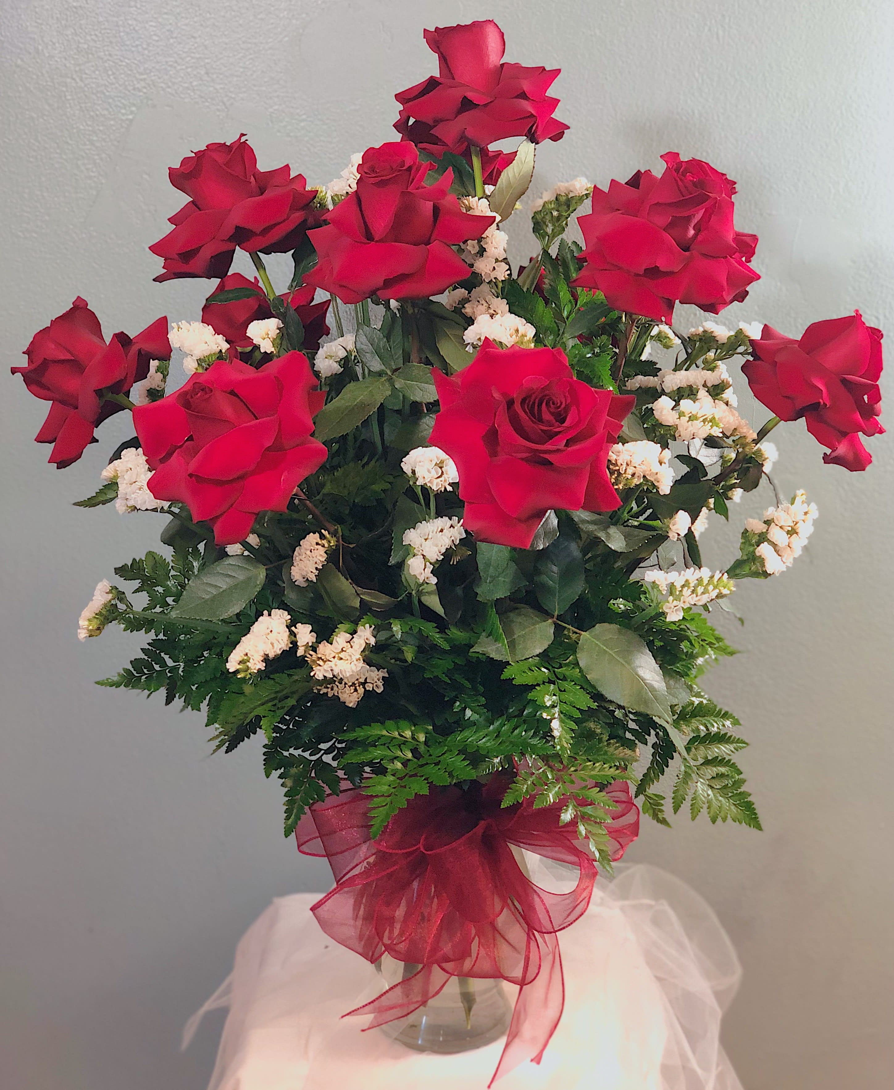 Red roses arranged in a clear glass vase with white filler flowers