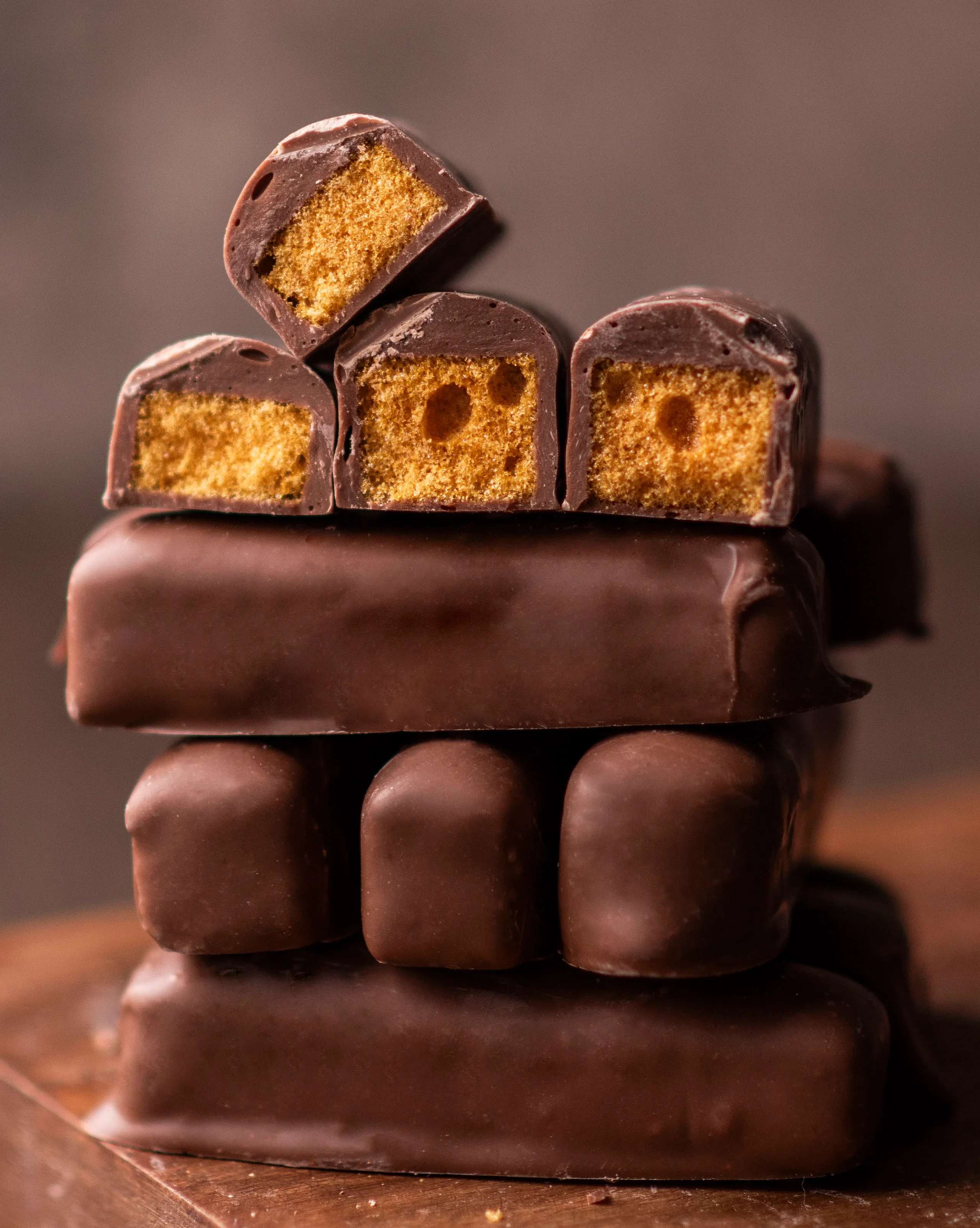 Stack of chocolate-covered candy bars with golden crunchy centers, some cut to show the inside.