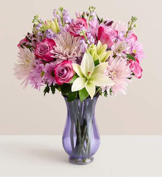 Pink and lavender mixed bouquet in a purple glass vase